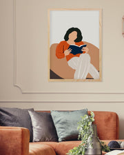 Framed artwork of a woman reading a book on a wall above a sofa.