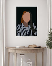 Framed portrait of a person with a blurred face on a wall above a wooden table.