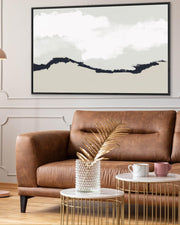 Living room with a brown leather sofa, gold coffee table, and abstract wall art.