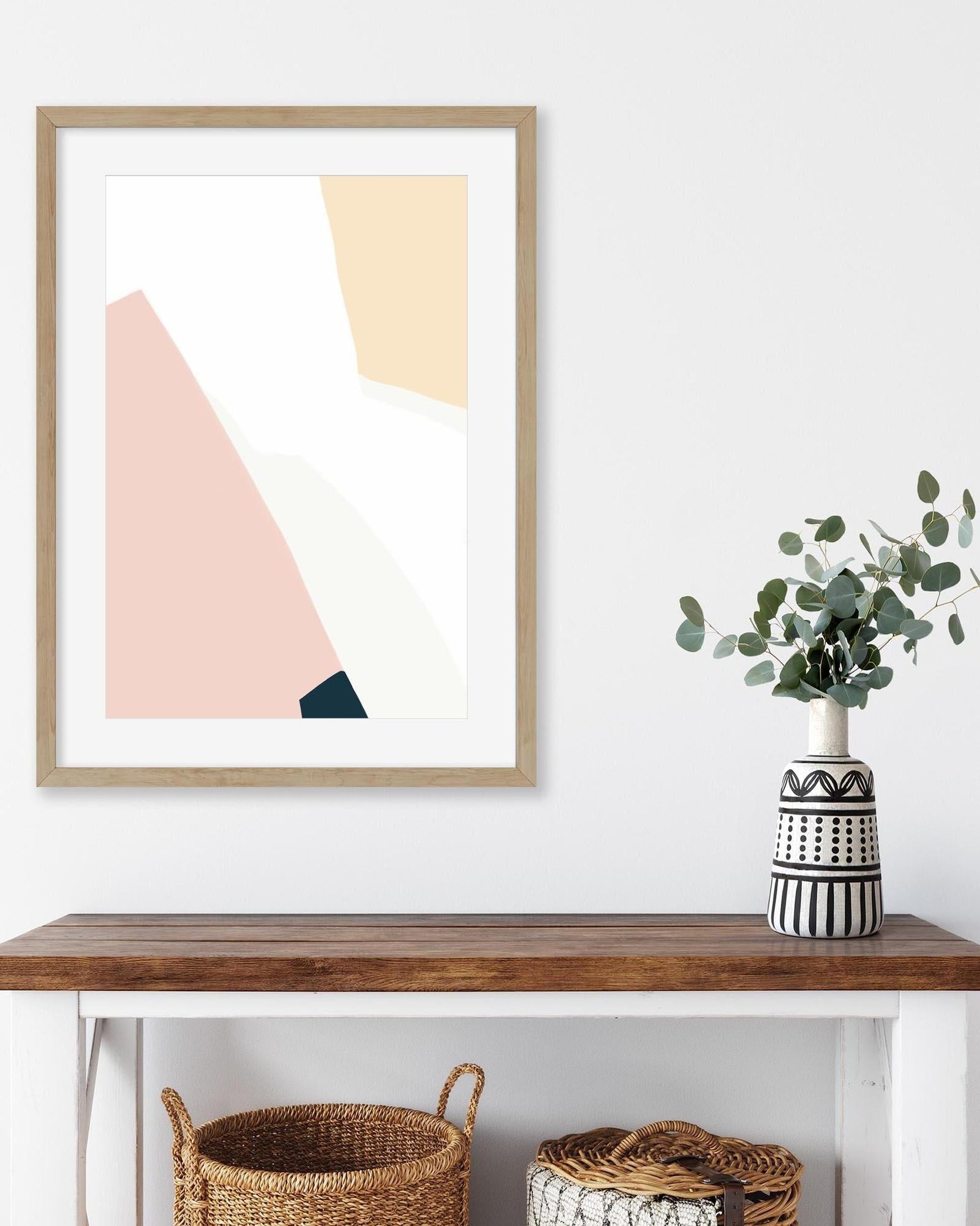 Framed abstract art on a wall above a wooden console table with decorative items.