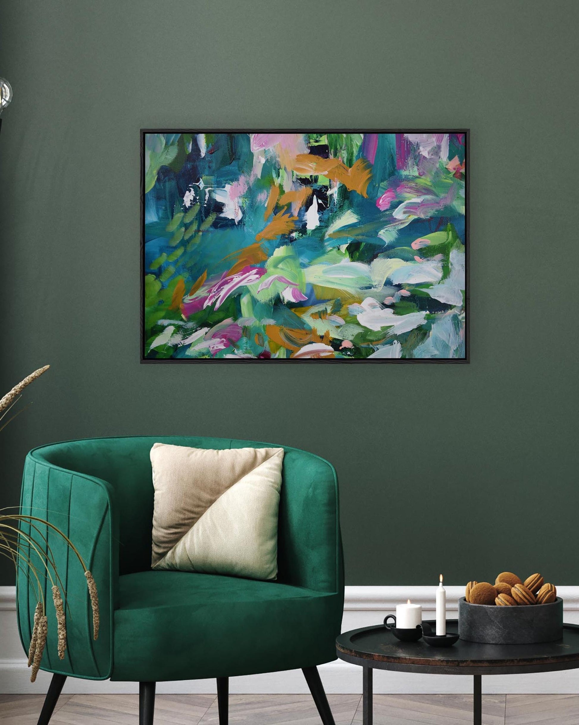 Green armchair with a colorful abstract painting on a dark green wall.