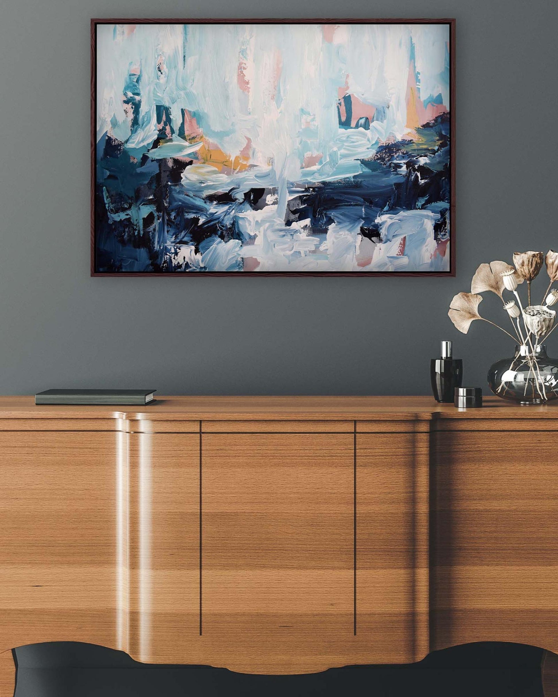 Abstract painting on a gray wall above a wooden cabinet.