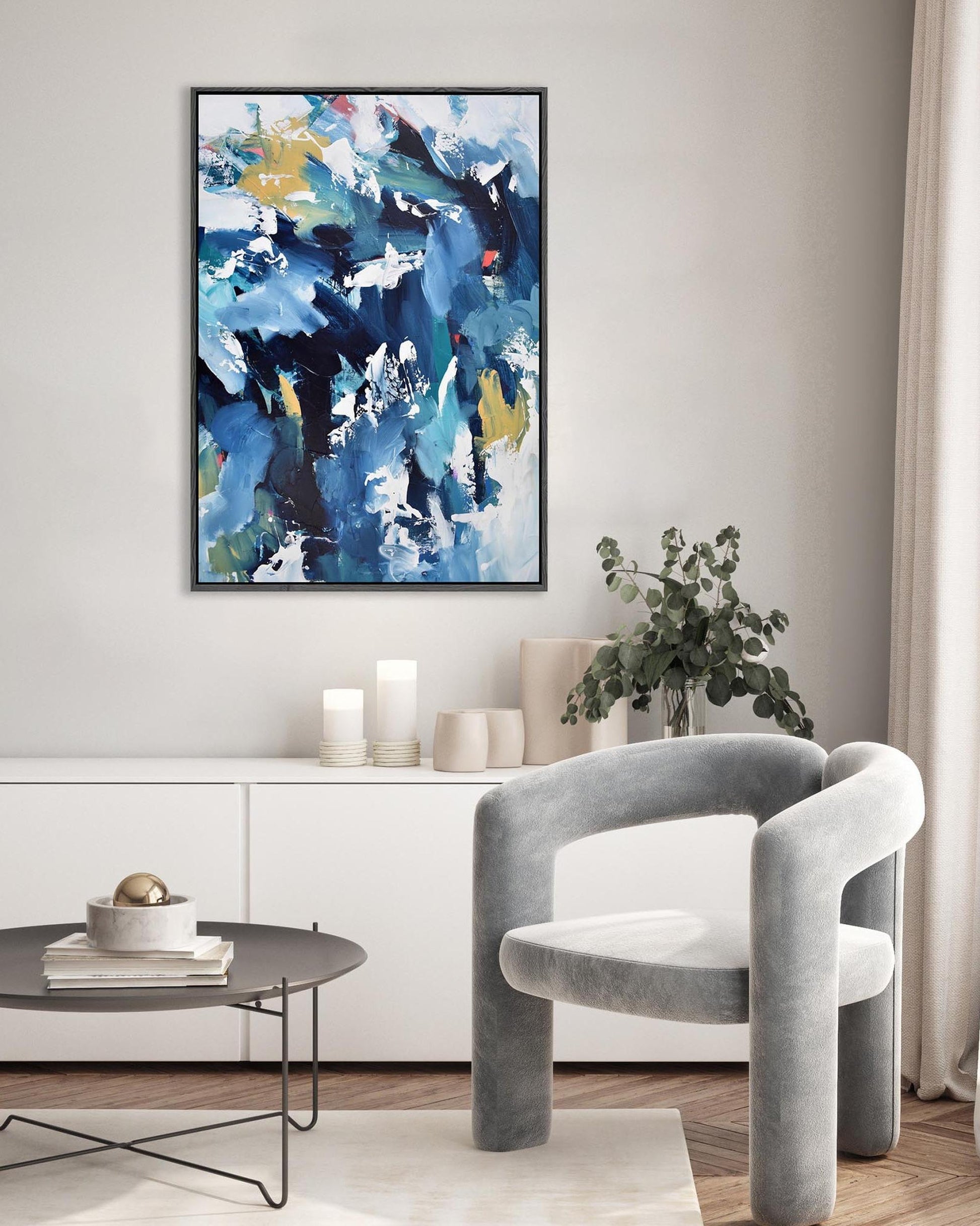 Modern living room with abstract art, gray chair, and decorative items.