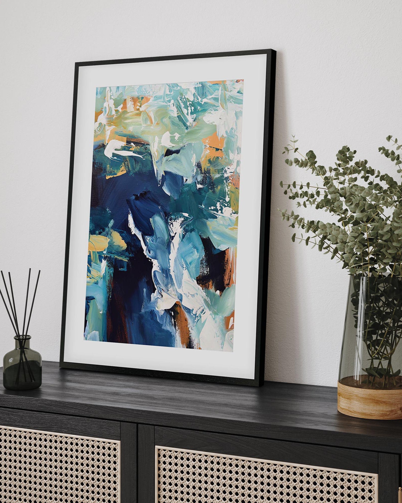 Framed abstract painting on a wall above a black cabinet with decorative items.