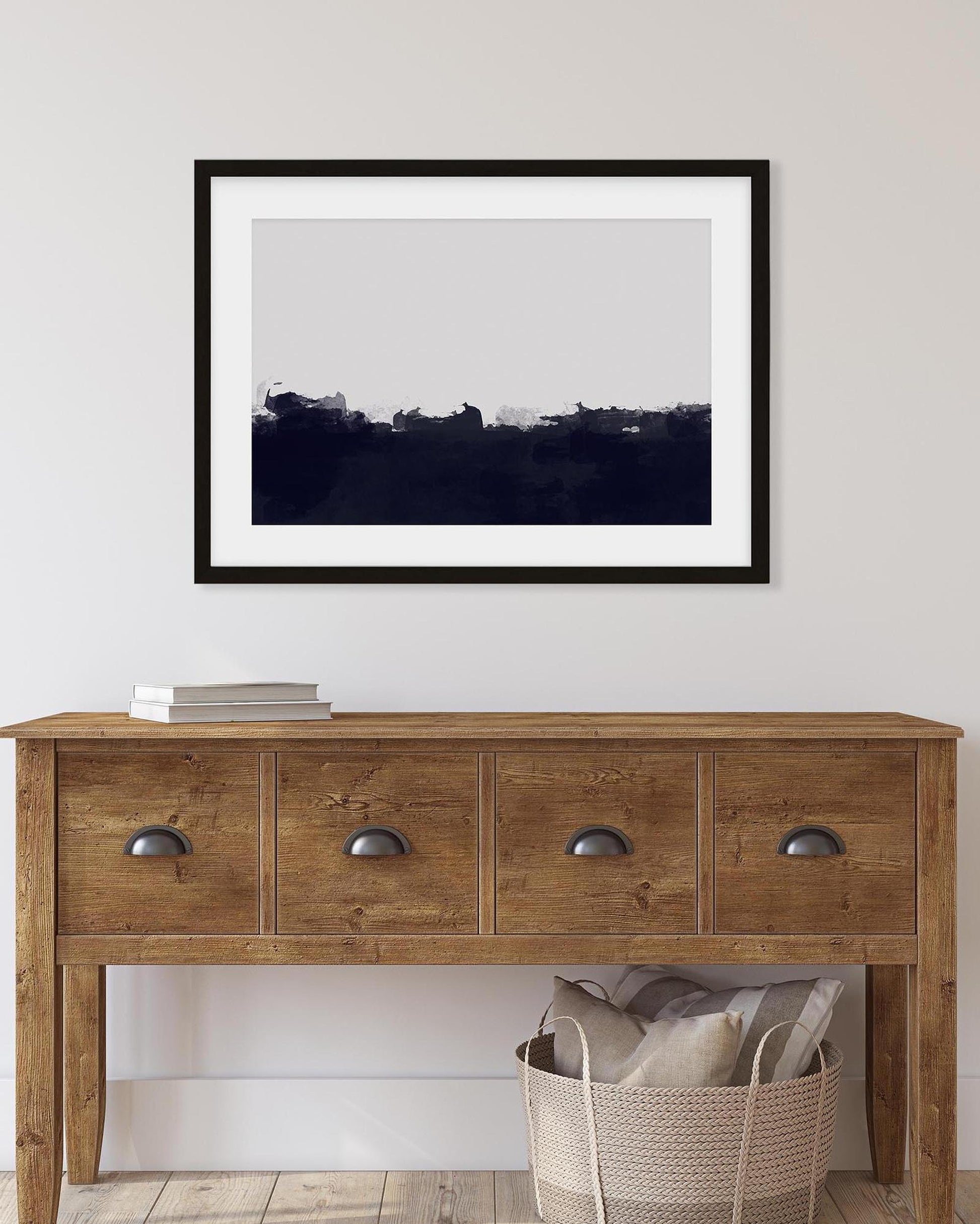 Wooden console table with a framed black and white landscape print on a white wall.