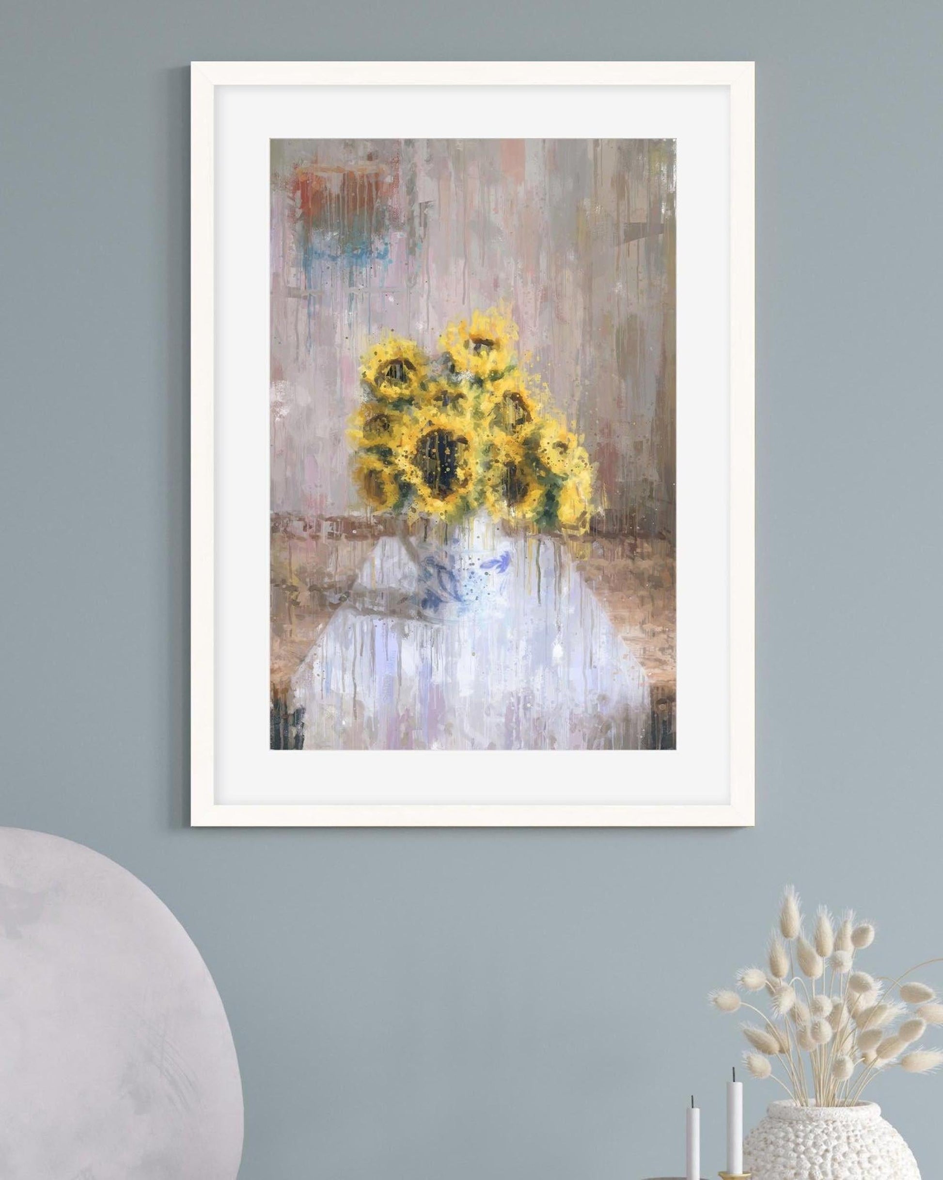 Framed artwork of sunflowers on a textured wall with decorative elements below.