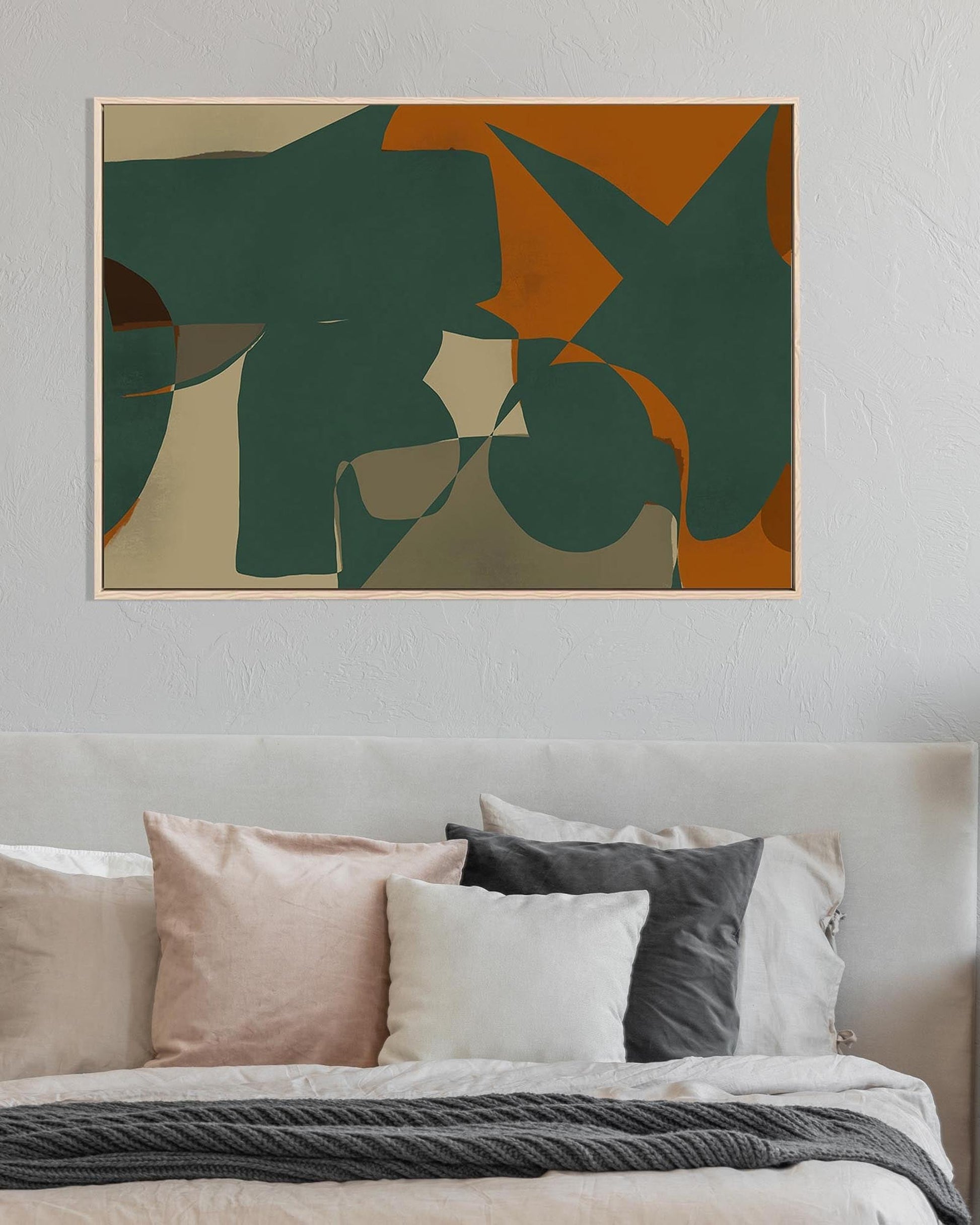 Abstract art piece on a wall above a bed with pillows