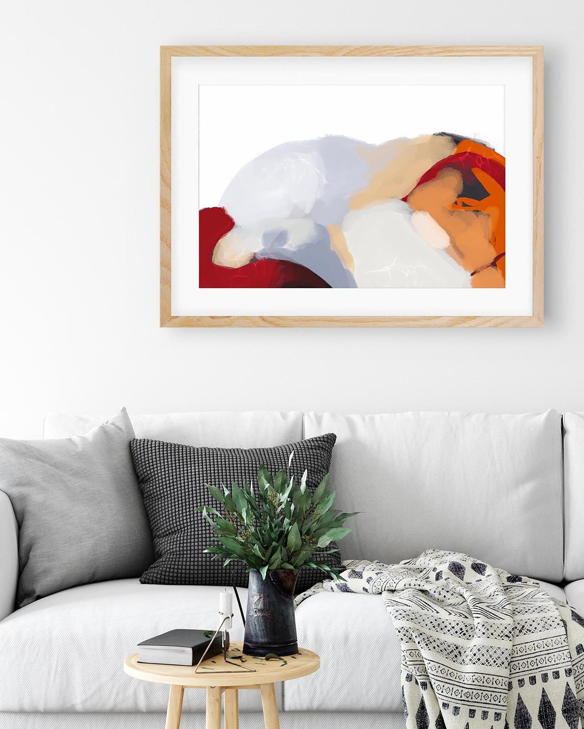Framed abstract art above a white sofa with decorative elements