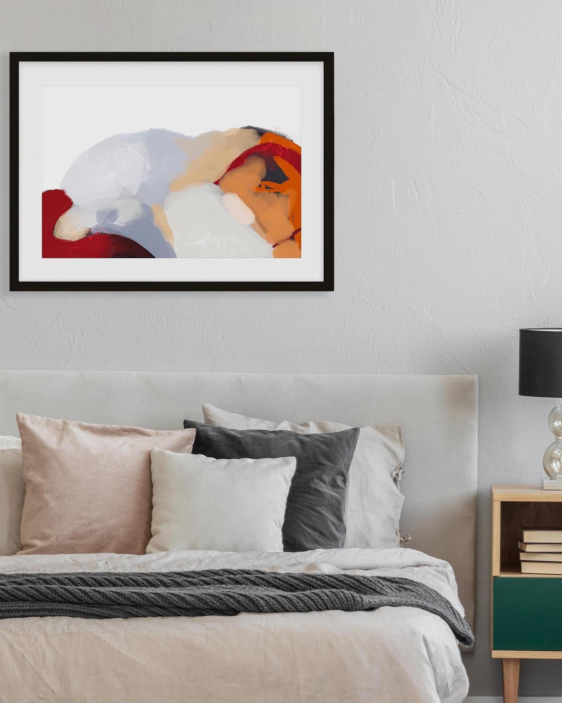 Framed abstract art above a bed with pillows and a nightstand.