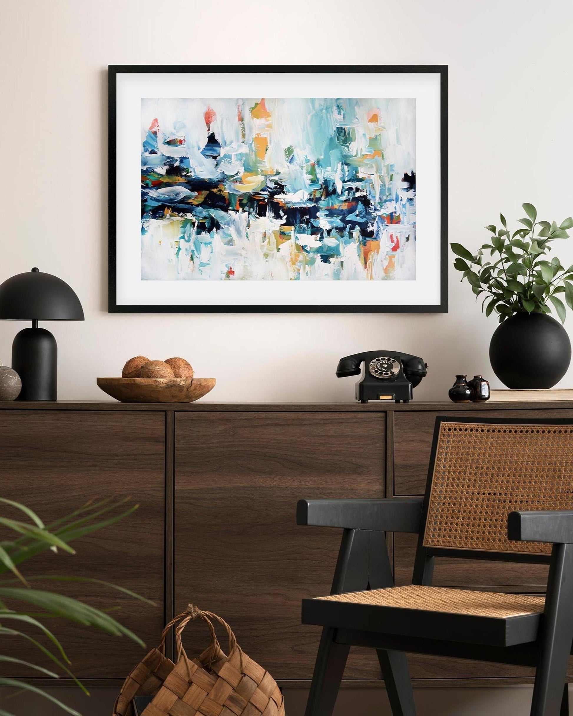 Framed abstract painting on a wall above a wooden console table with decorative items.