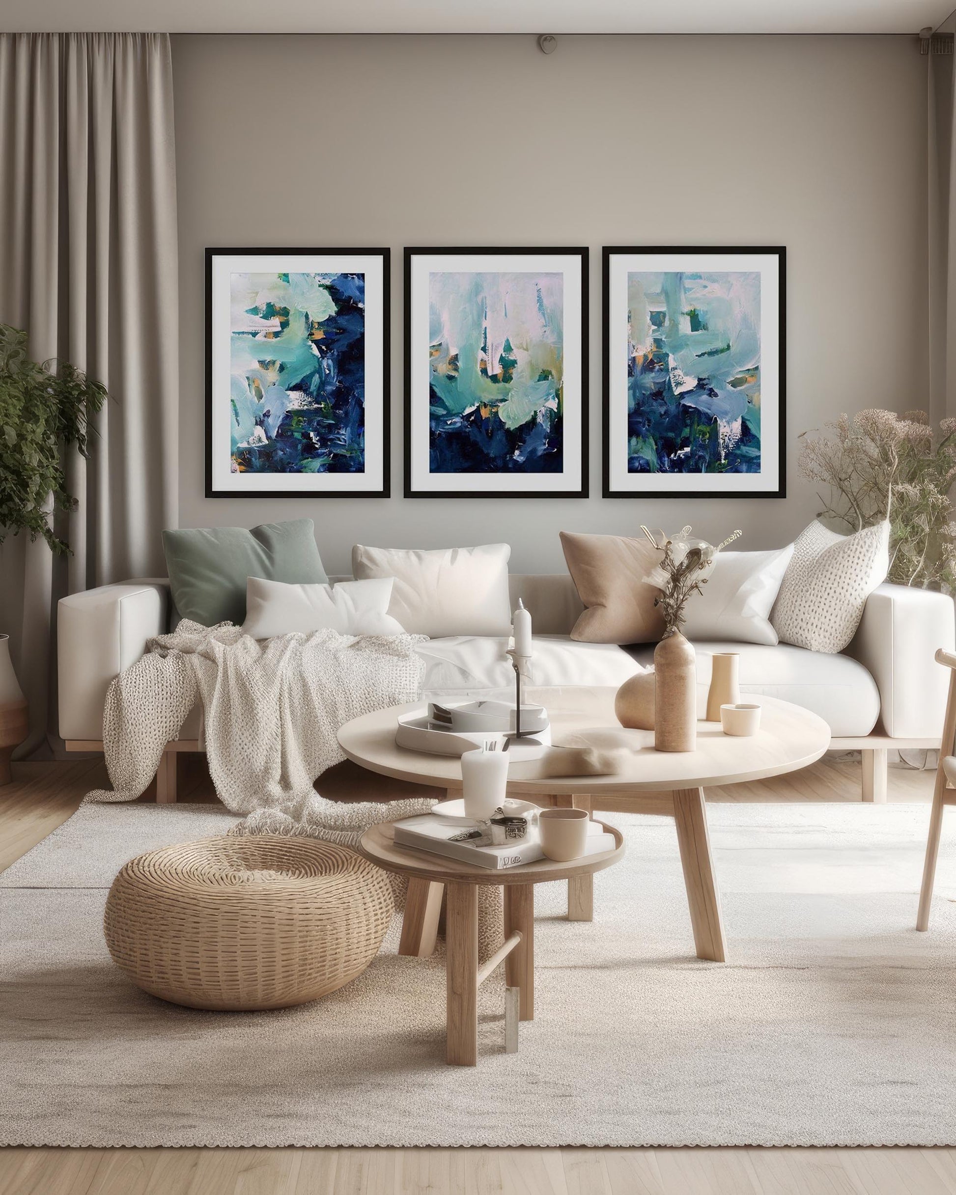 A set of three abstract landscape art prints mounted on a wall above a sofa in a room with neutral decor.
