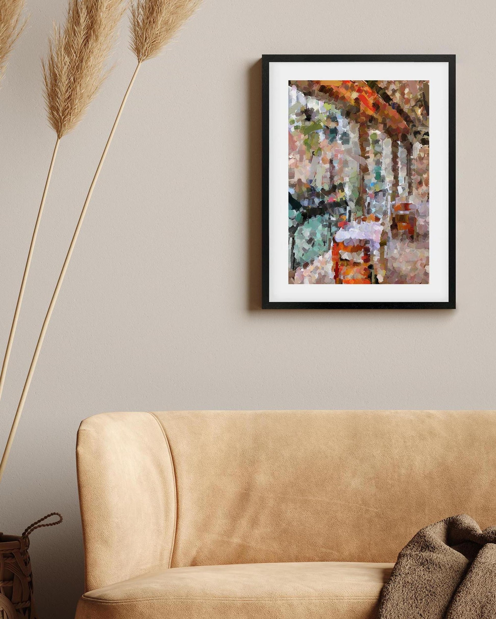 Framed abstract painting on a wall above a beige sofa with decorative elements.