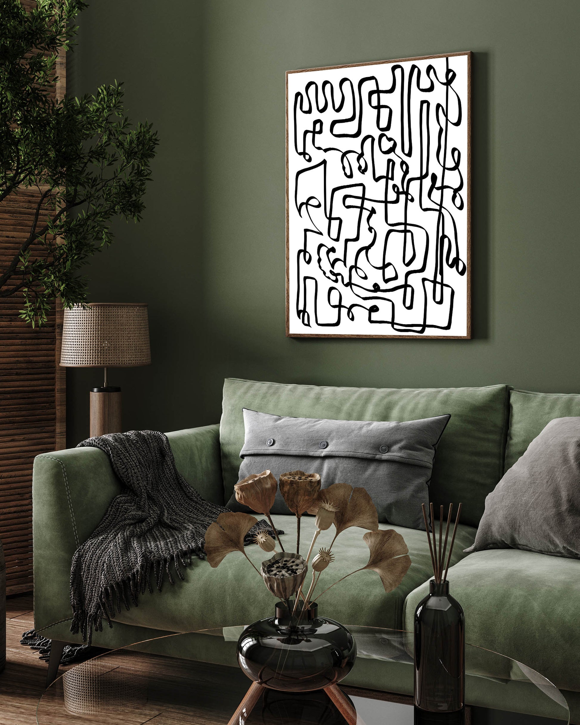 A framed canvas with a black, curved line abstract design hanging on a green wall above a sofa with cushions, with a plant and a lamp in the room.