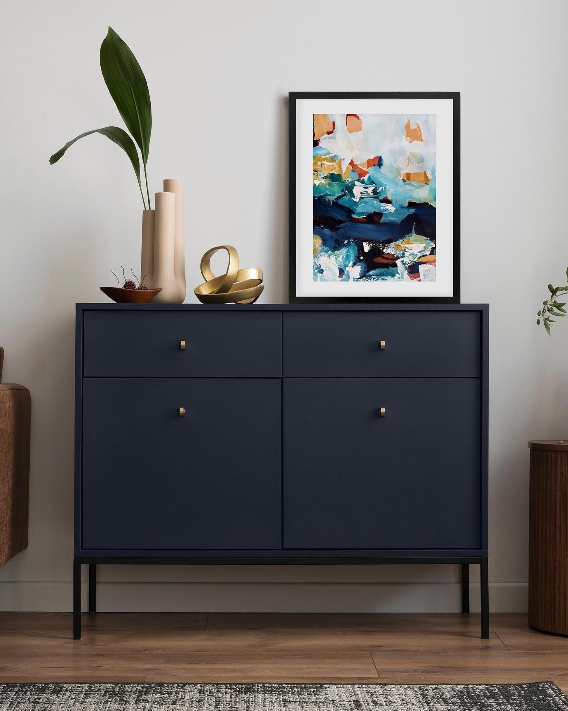 Navy blue sideboard with decorative items and a colorful abstract painting in a living room setting.