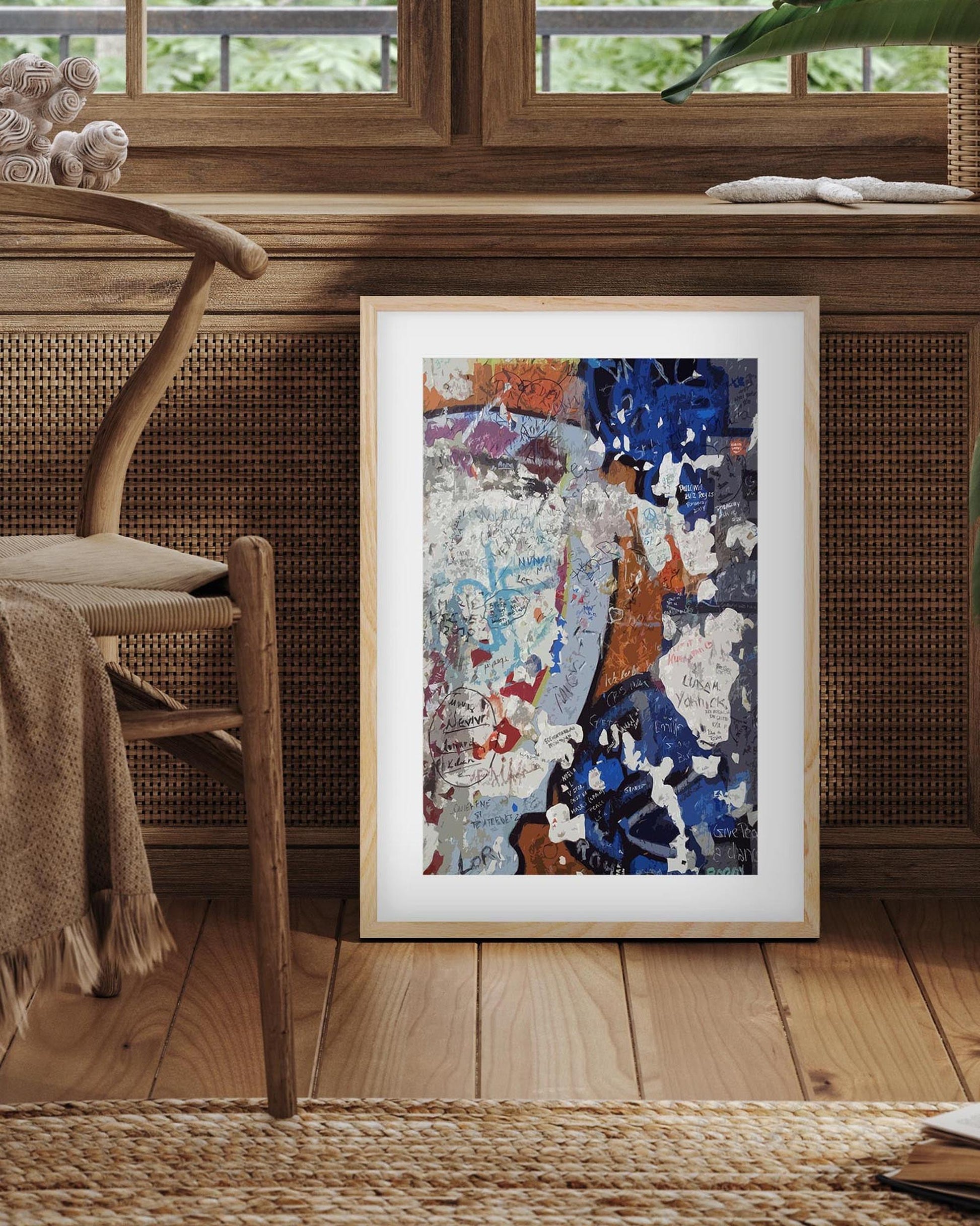 Framed abstract artwork on a wooden floor with a chair and woven basket in the background