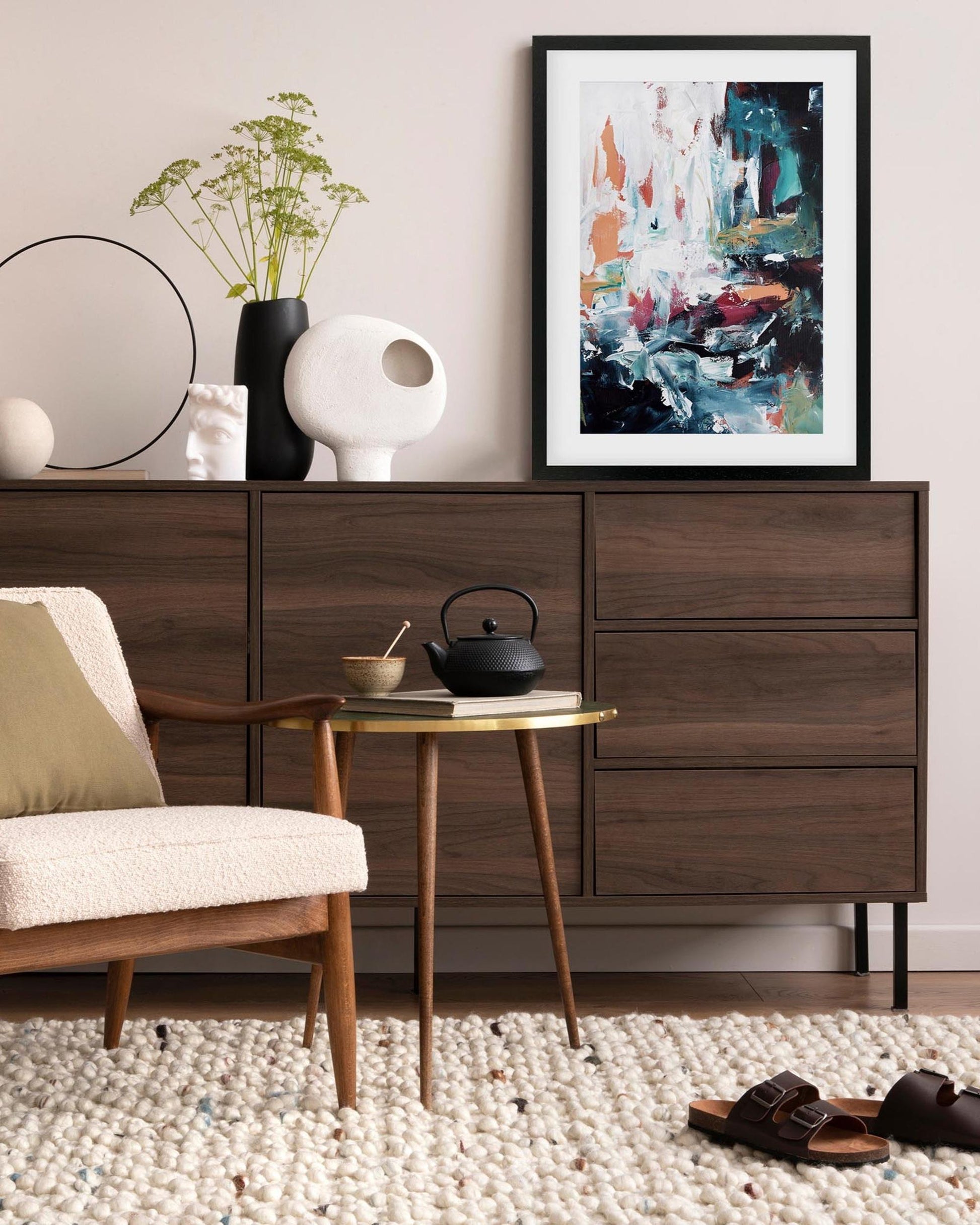Modern living room with wooden dresser, chair, and abstract art on the wall.