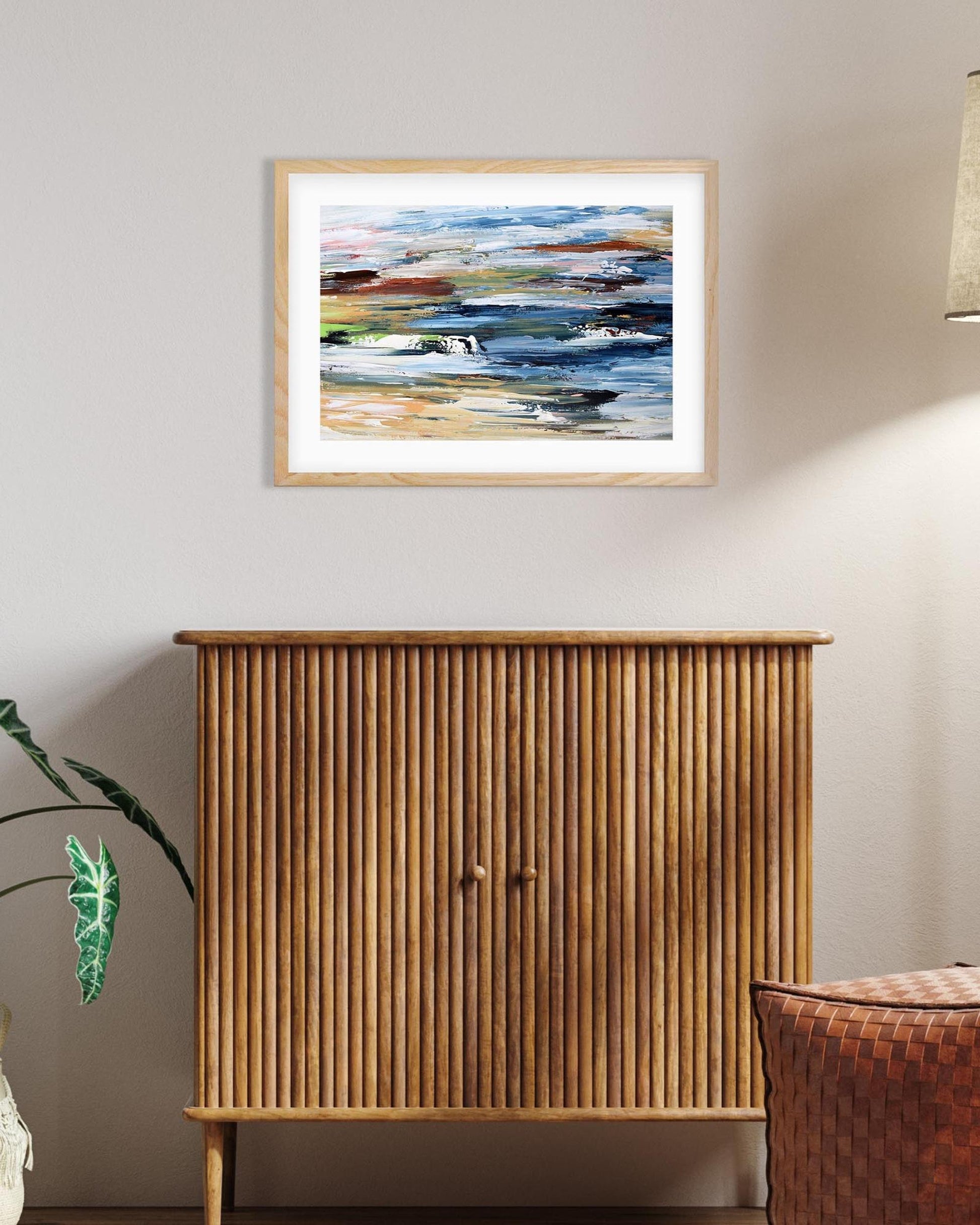 Wooden cabinet with a framed abstract painting on a wall