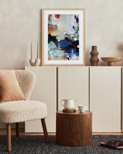 Living room with a textured armchair, wooden side table, and abstract art on the wall.