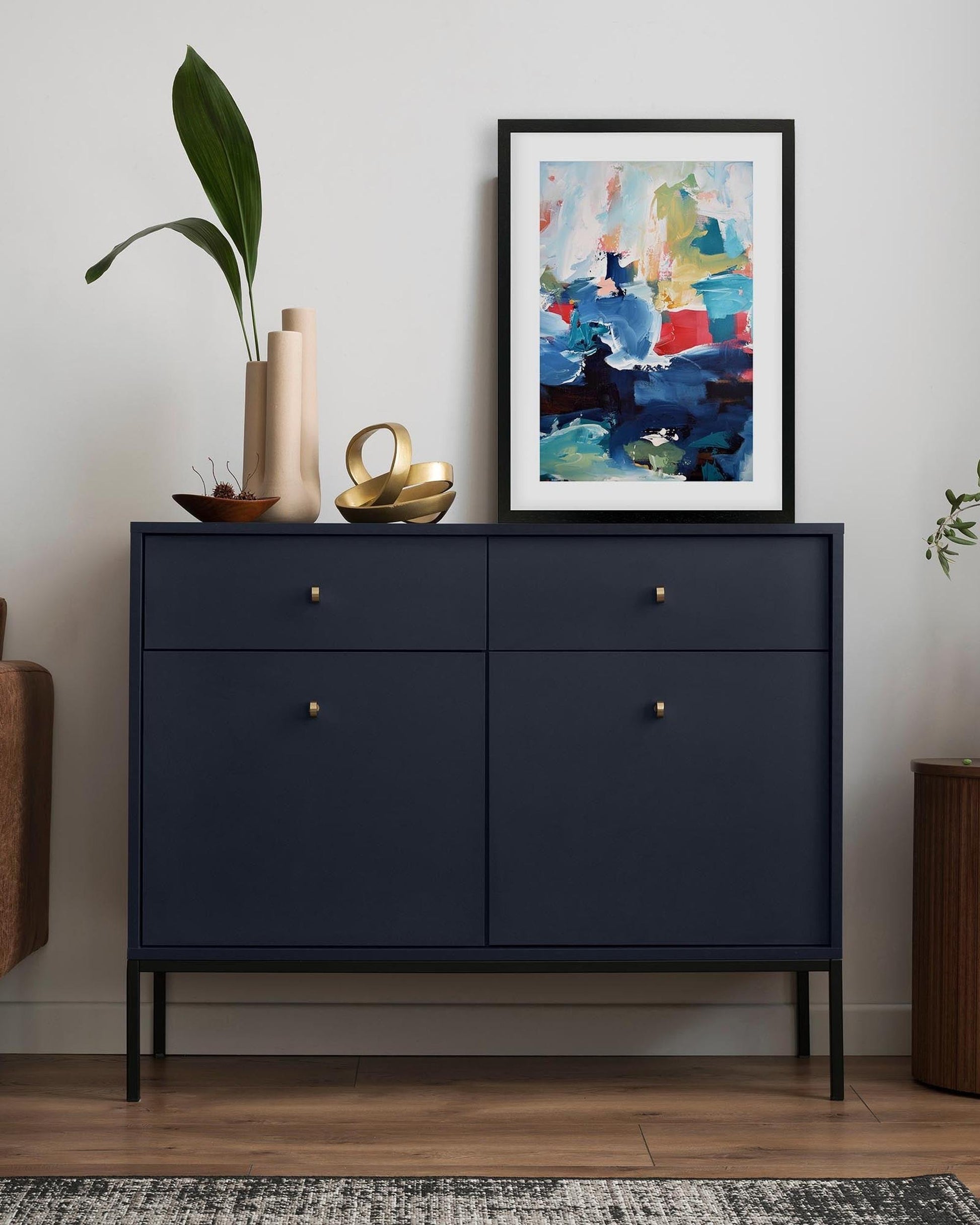 Navy blue cabinet with decorative items and a colorful abstract painting on a white wall.