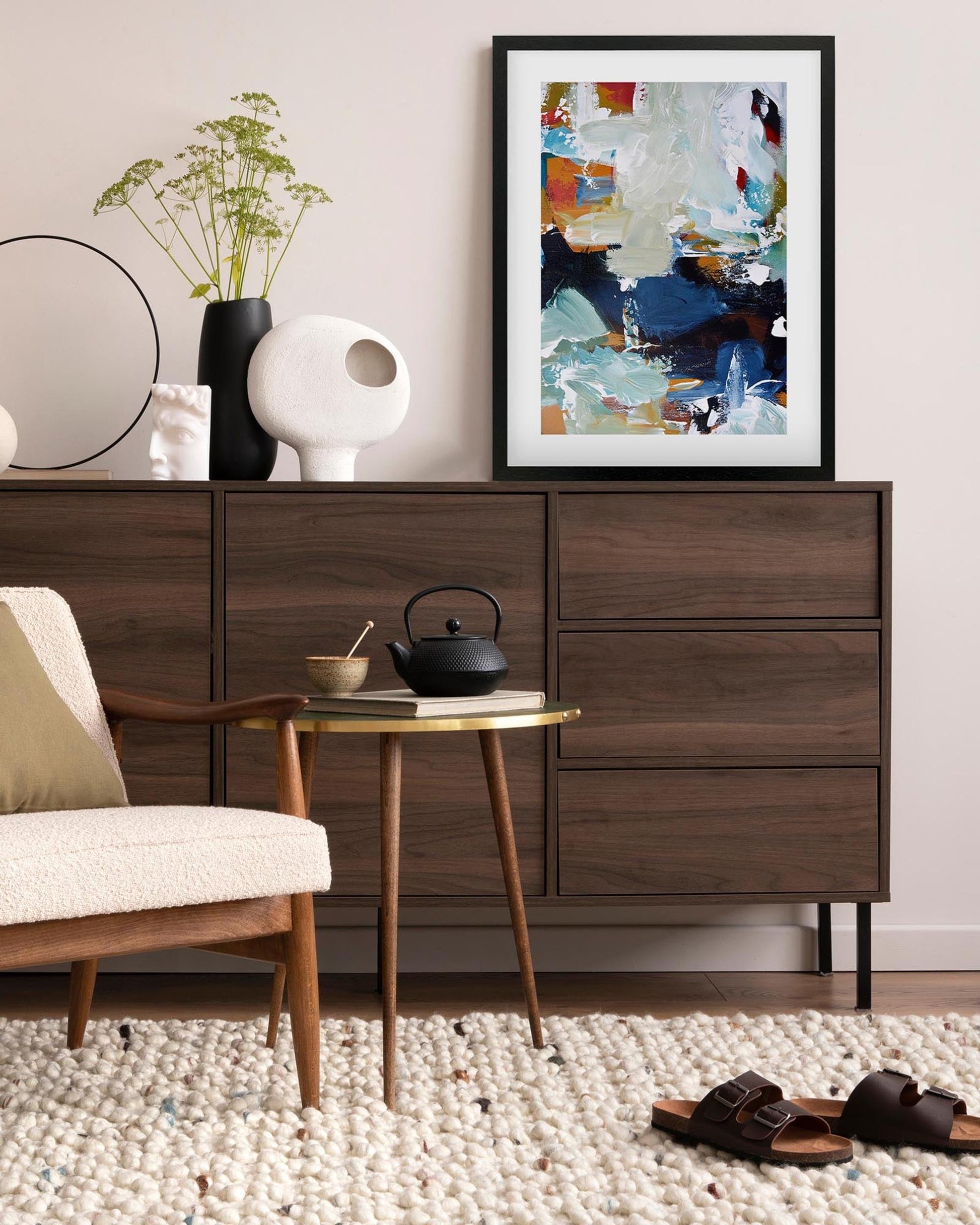 Modern living room with wooden sideboard, chair, and abstract art on the wall.