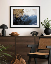 Framed abstract artwork on a wall above a wooden console table with decorative items.