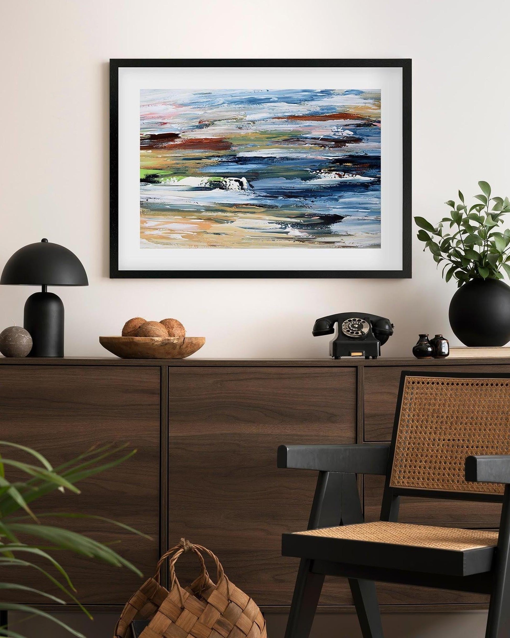 Framed abstract painting on a wall above a wooden console table with decorative items.