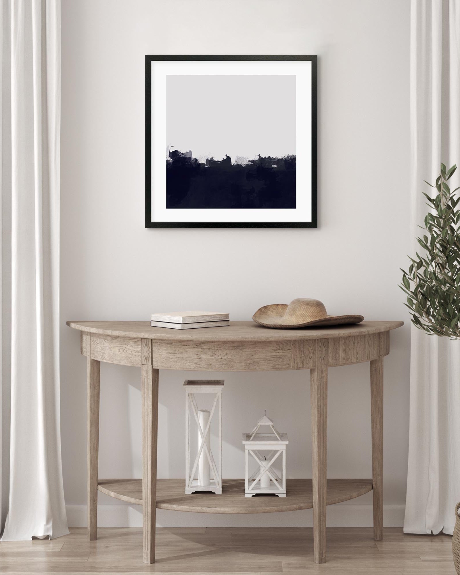 Wooden console table with decorative items against a white wall with a framed picture.