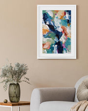 Framed abstract art on a wall above a sofa and side table with a vase.