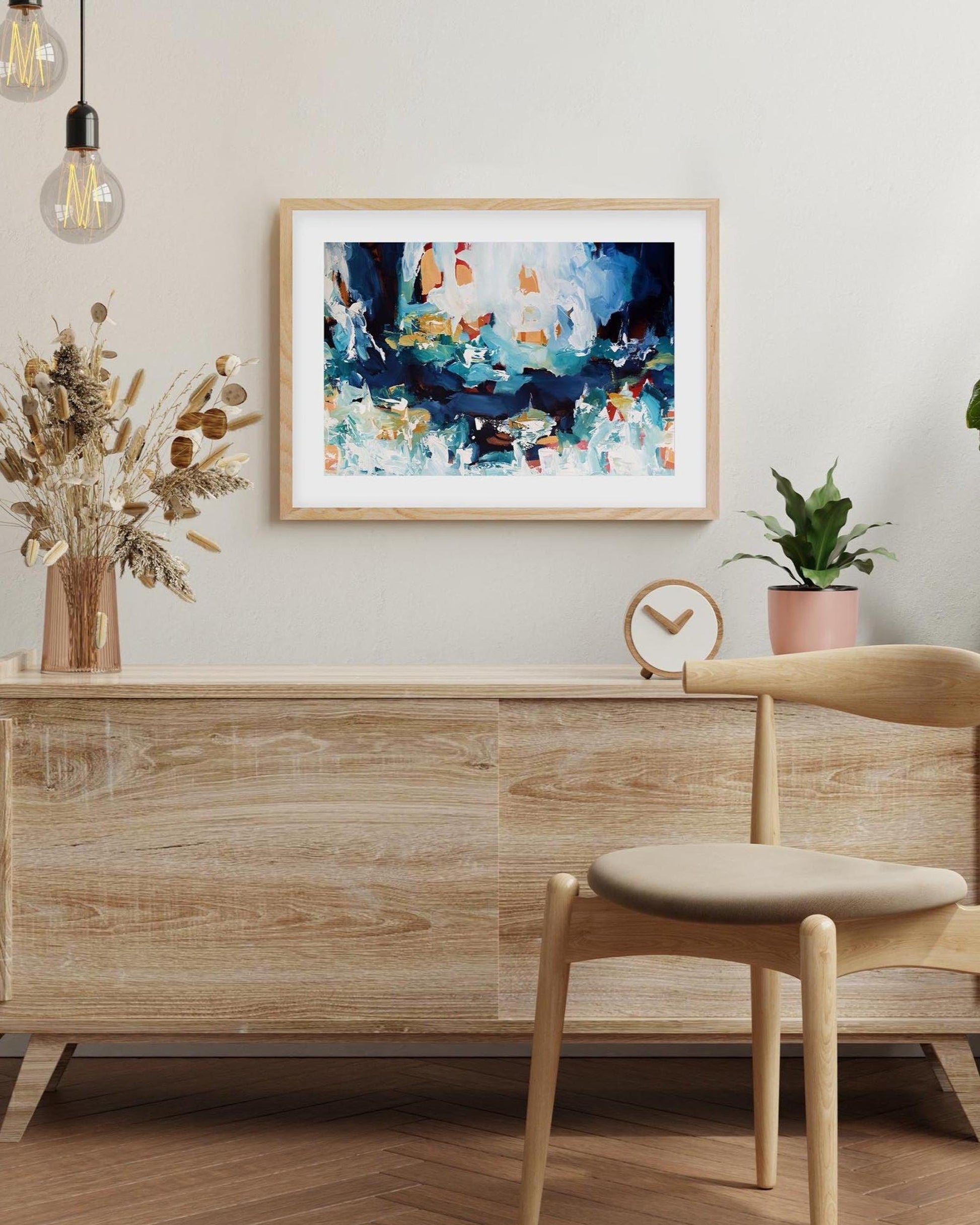 Modern interior with wooden sideboard, chair, and abstract art on the wall.