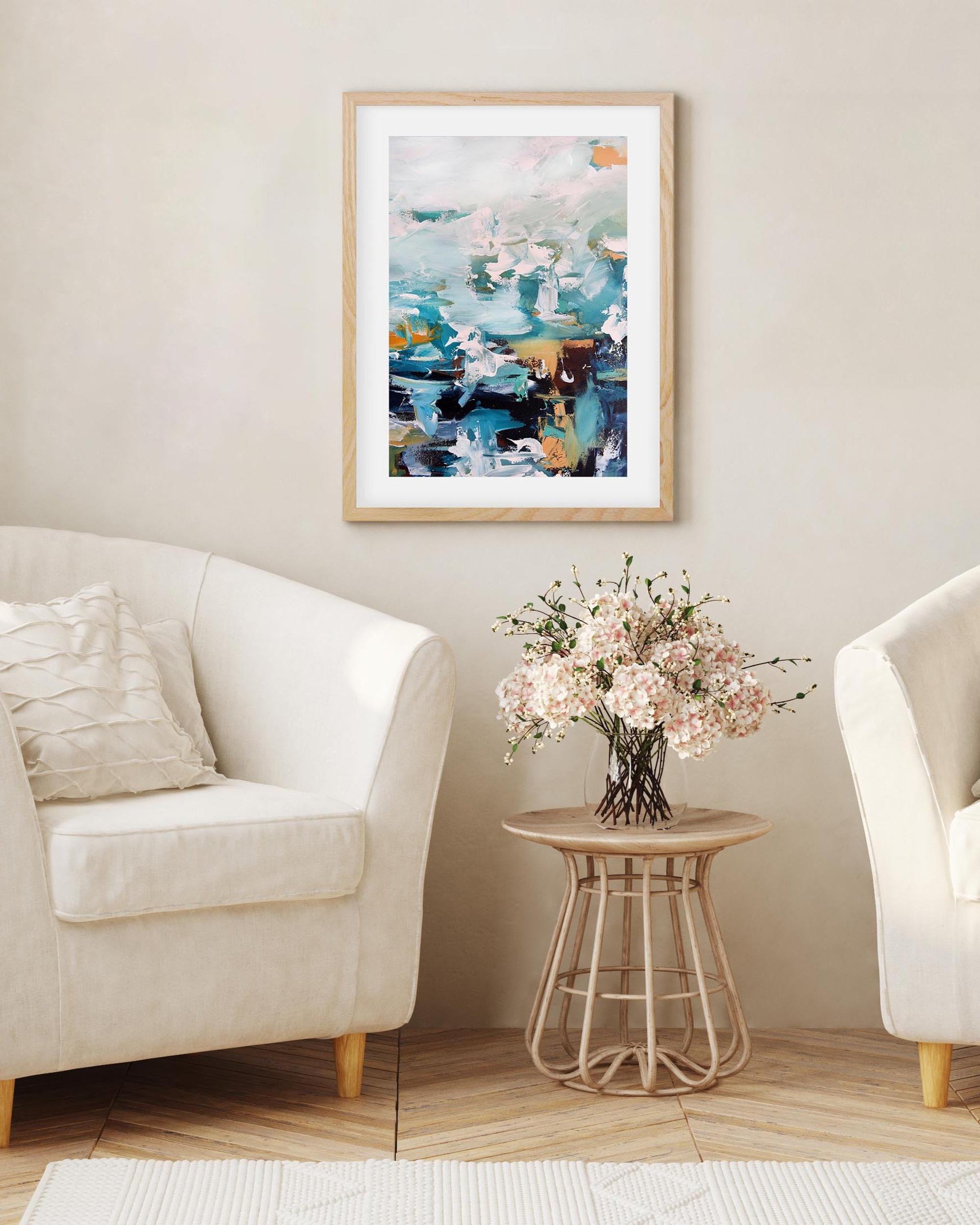 Living room with two white armchairs, a small table with flowers, and a colorful abstract painting on the wall.