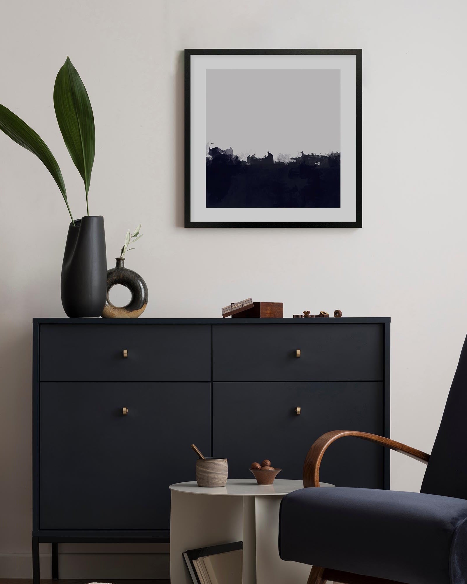 Modern interior with a black dresser, framed artwork, and decorative items.