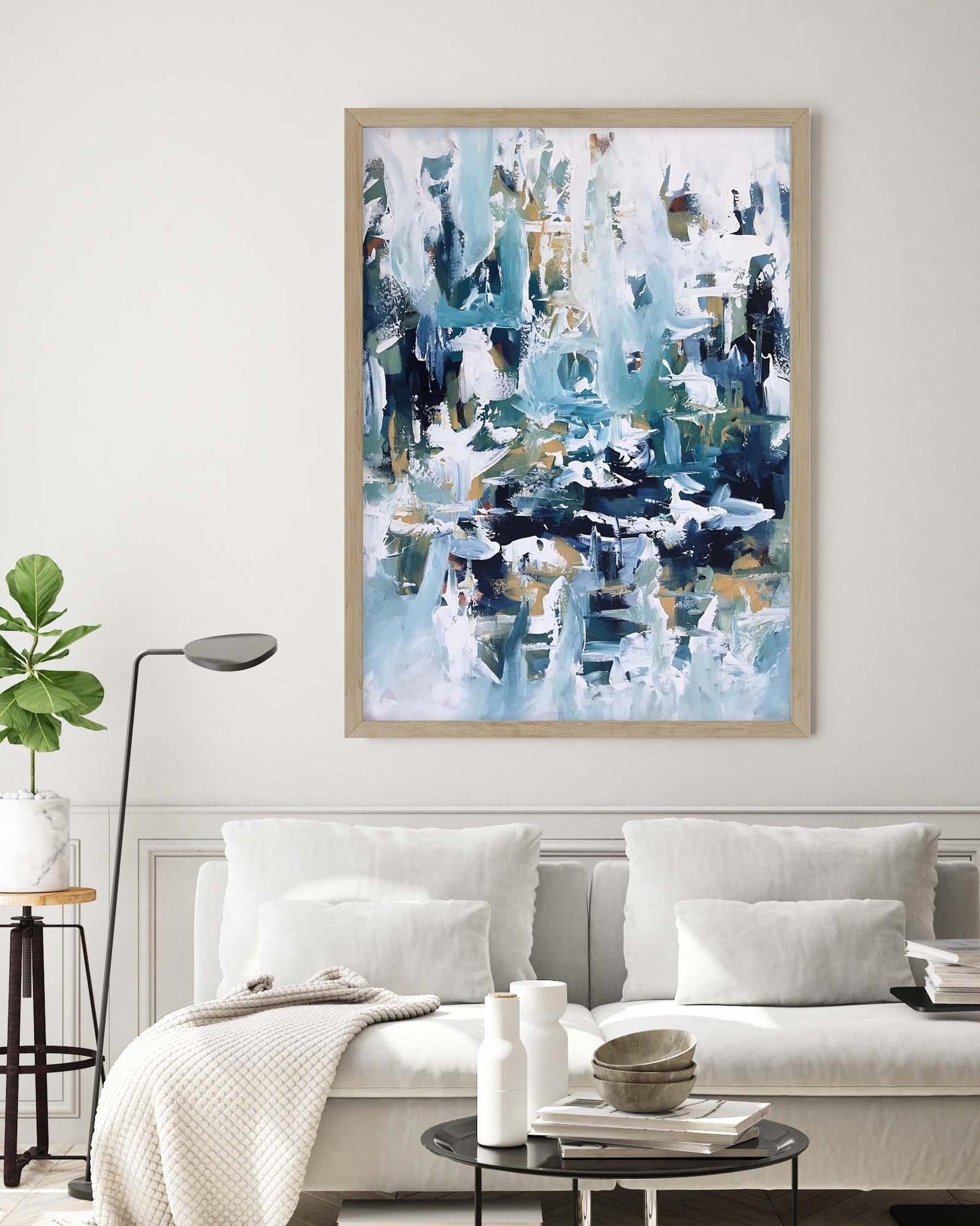 Abstract art print in a living room setting with a sofa and lamp.