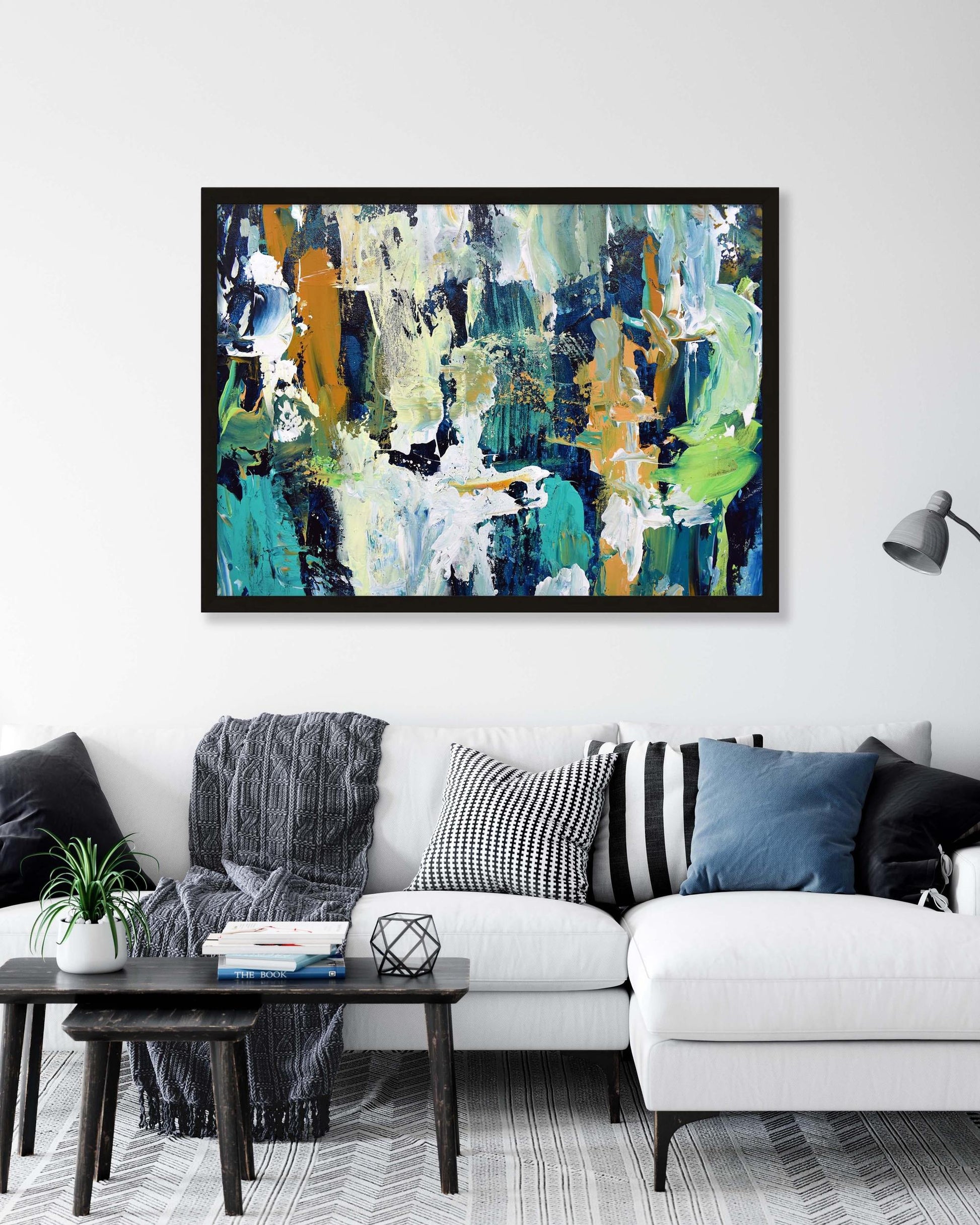 Abstract painting on a wall above a white sofa with decorative pillows.