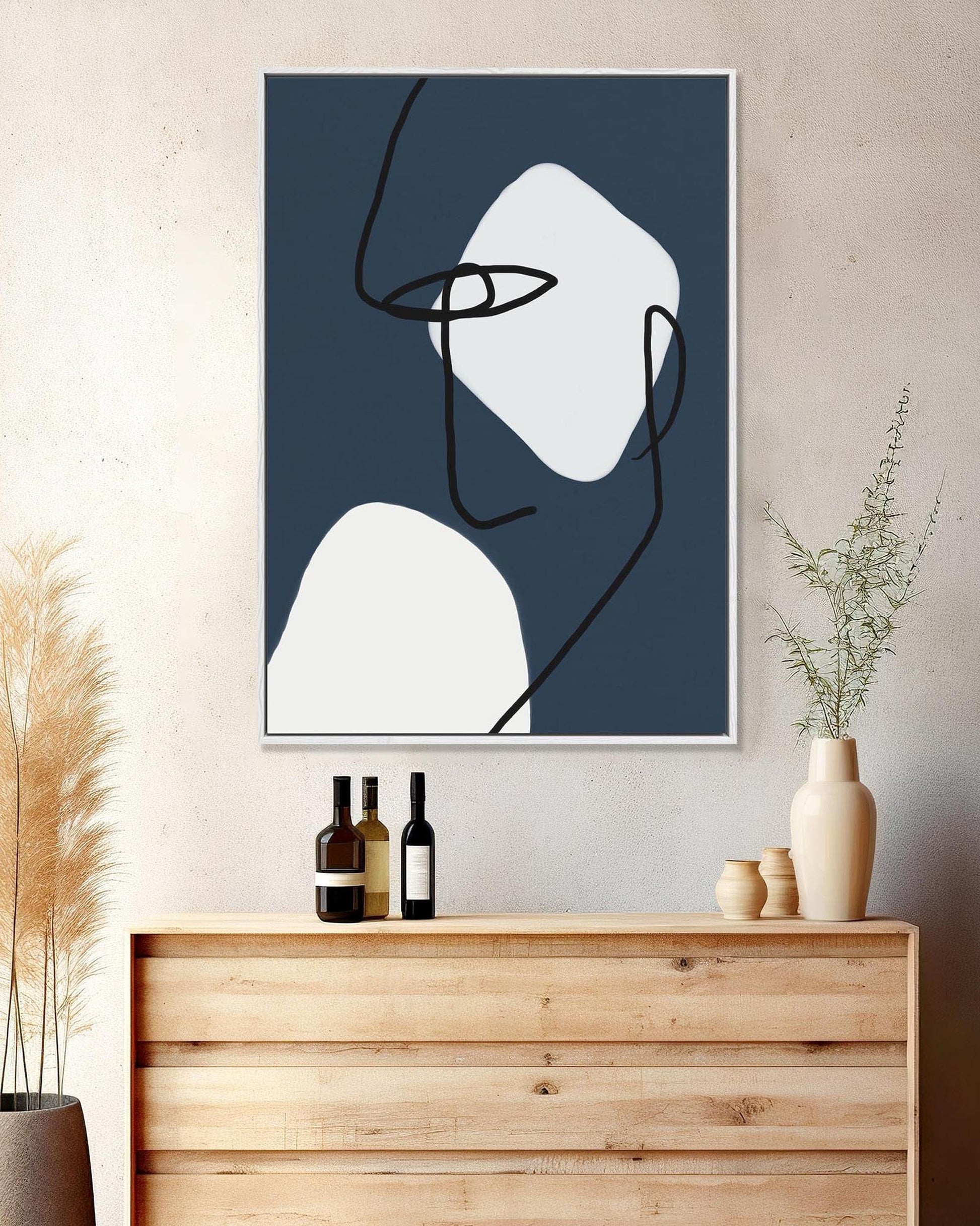 Abstract art print on a wall above a wooden cabinet with decorative items.