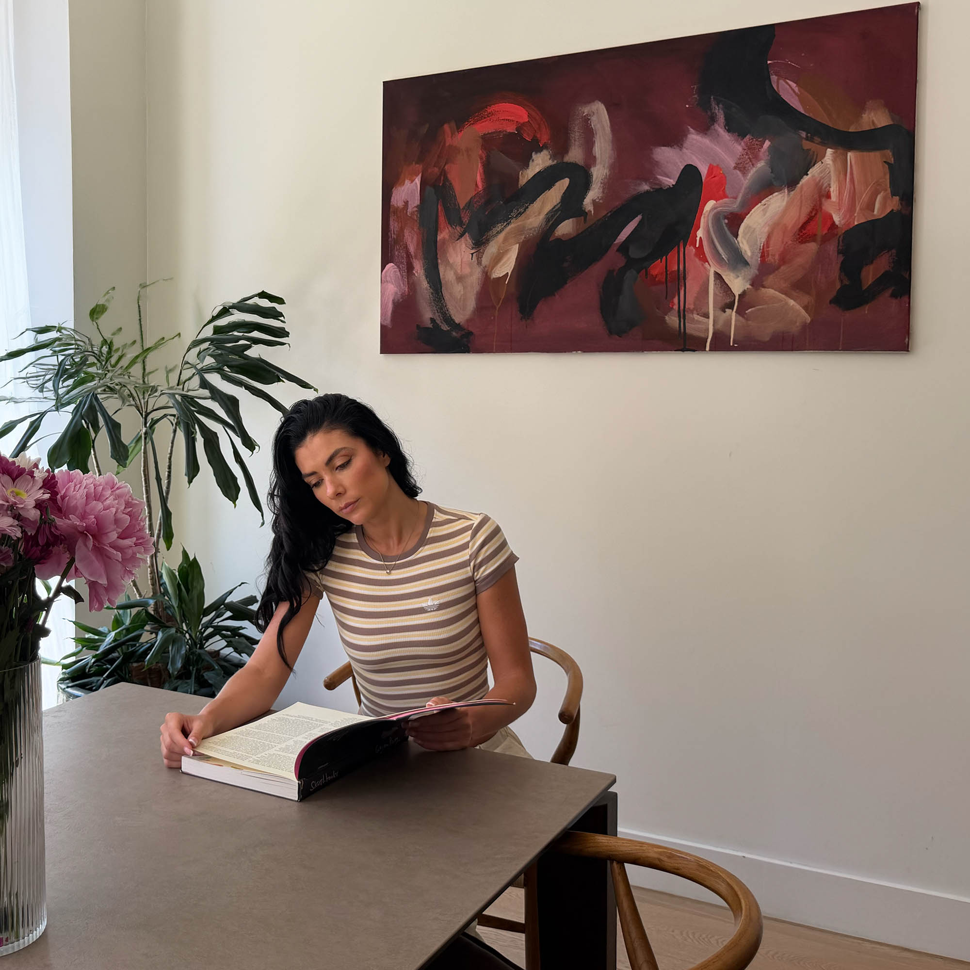 large abstract original painting on a wall with a woman sitting on a modern dining table