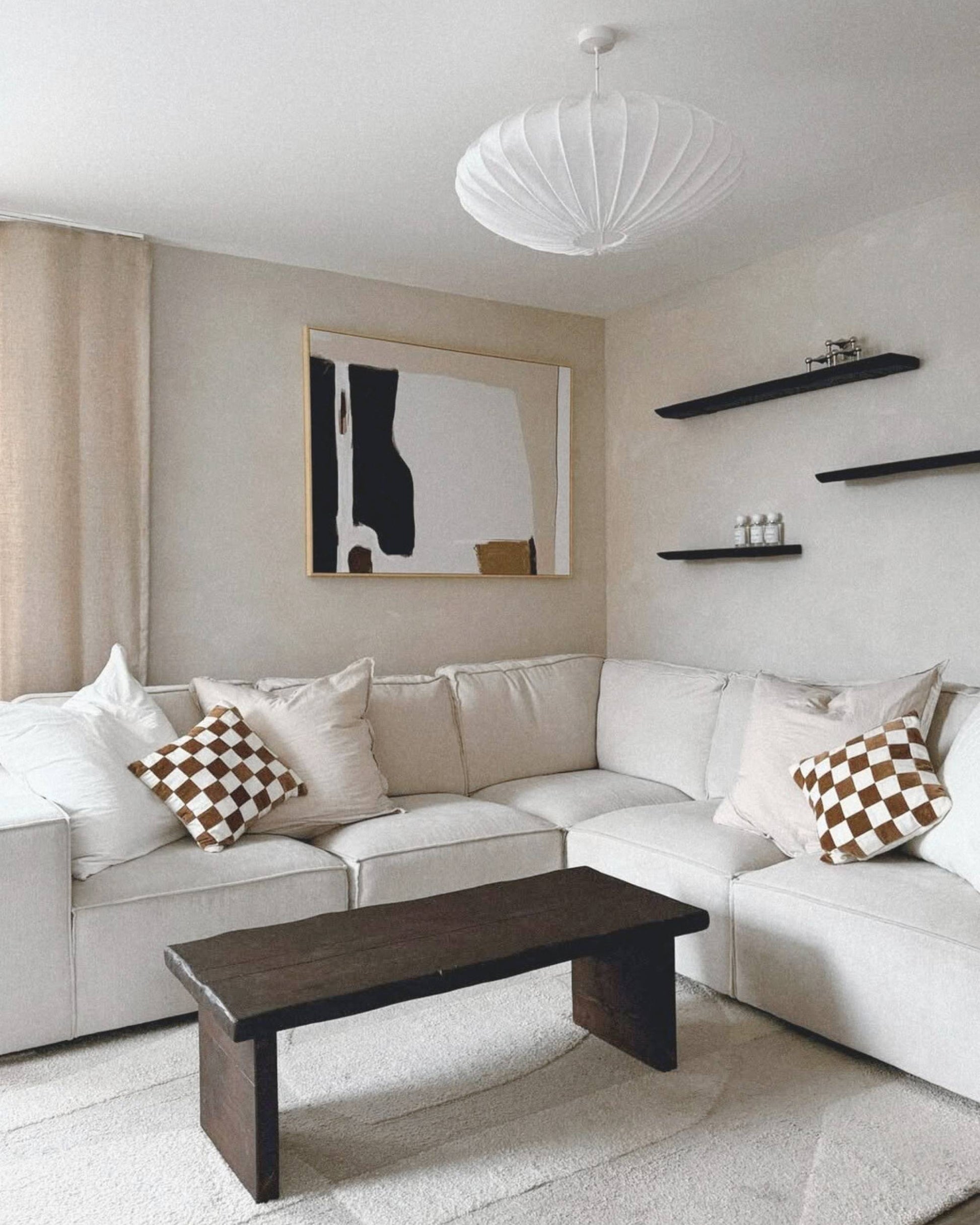 Modern living room with a white sectional sofa, wooden coffee table, and abstract art on the wall. Japandi themed modern wall art large neutral print on canvas.