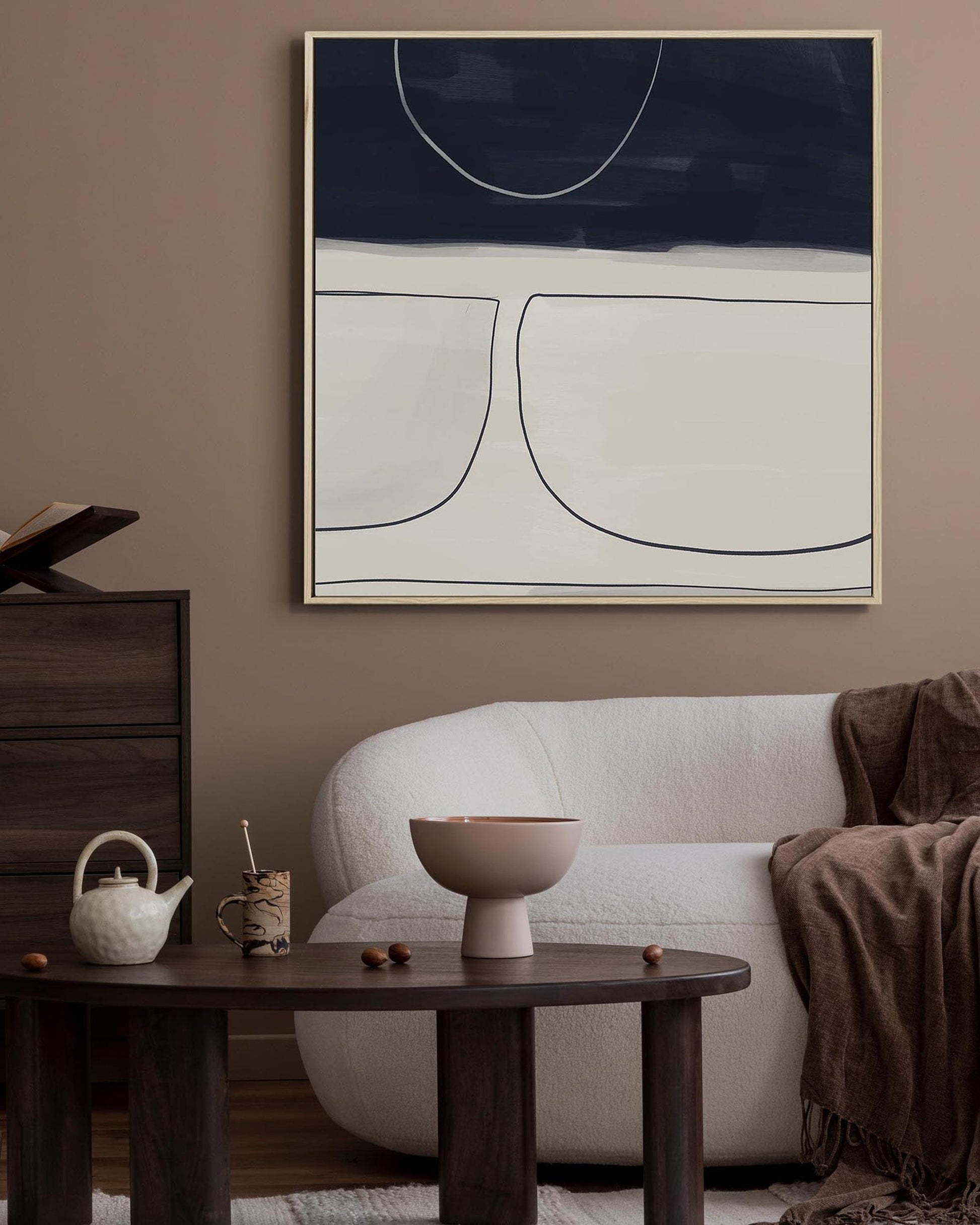 Modern living room with a white sofa, wooden side table, and abstract art on the wall.