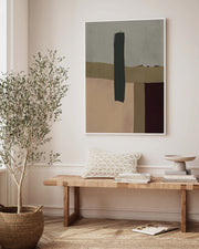 A framed canvas abstract art piece with brown shapes displayed above a bench with decorative pillows, a tree in a basket, and some books in a bright interior setting.
