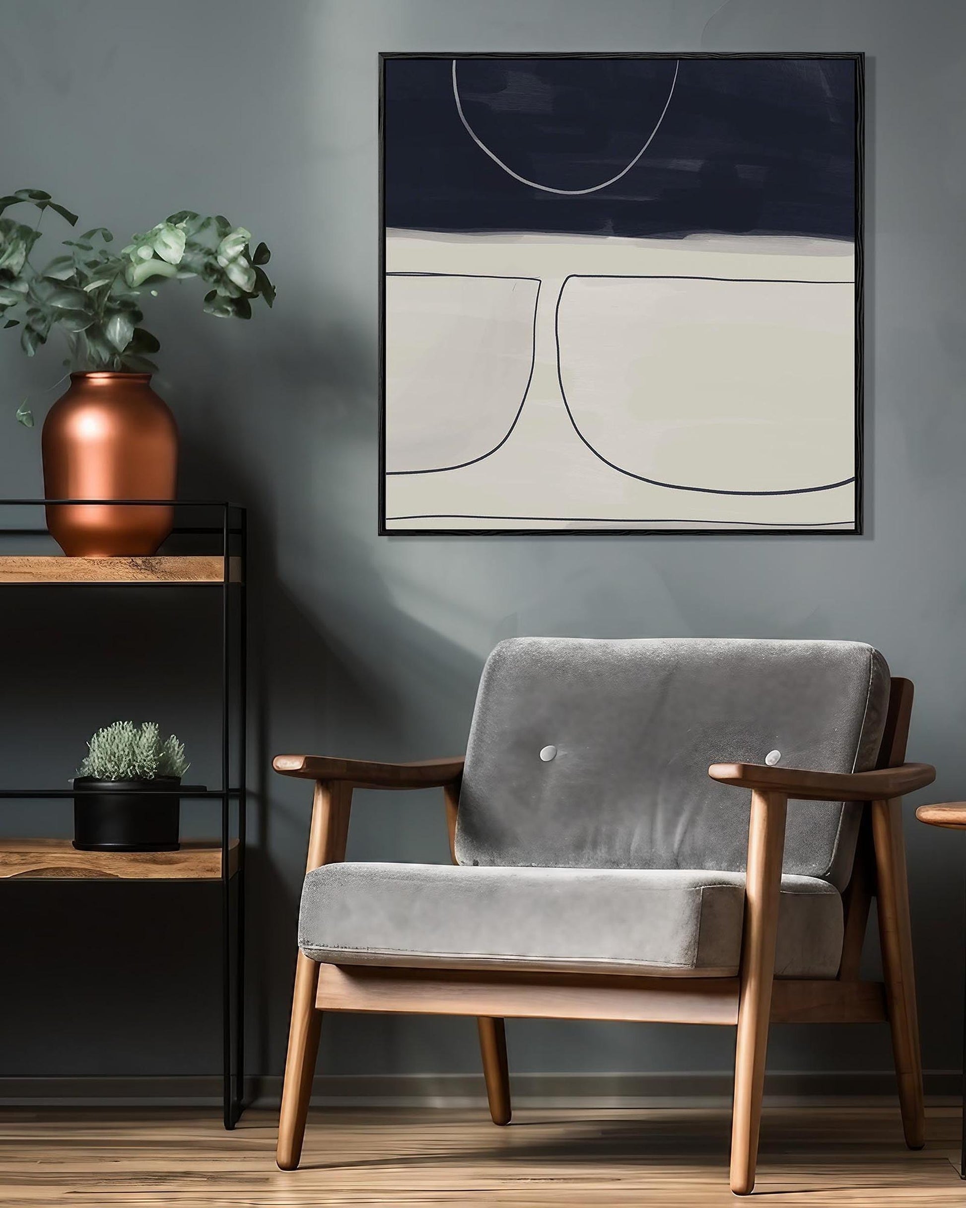 Gray armchair in a room with a abstract painting on the wall and a plant on a shelf.