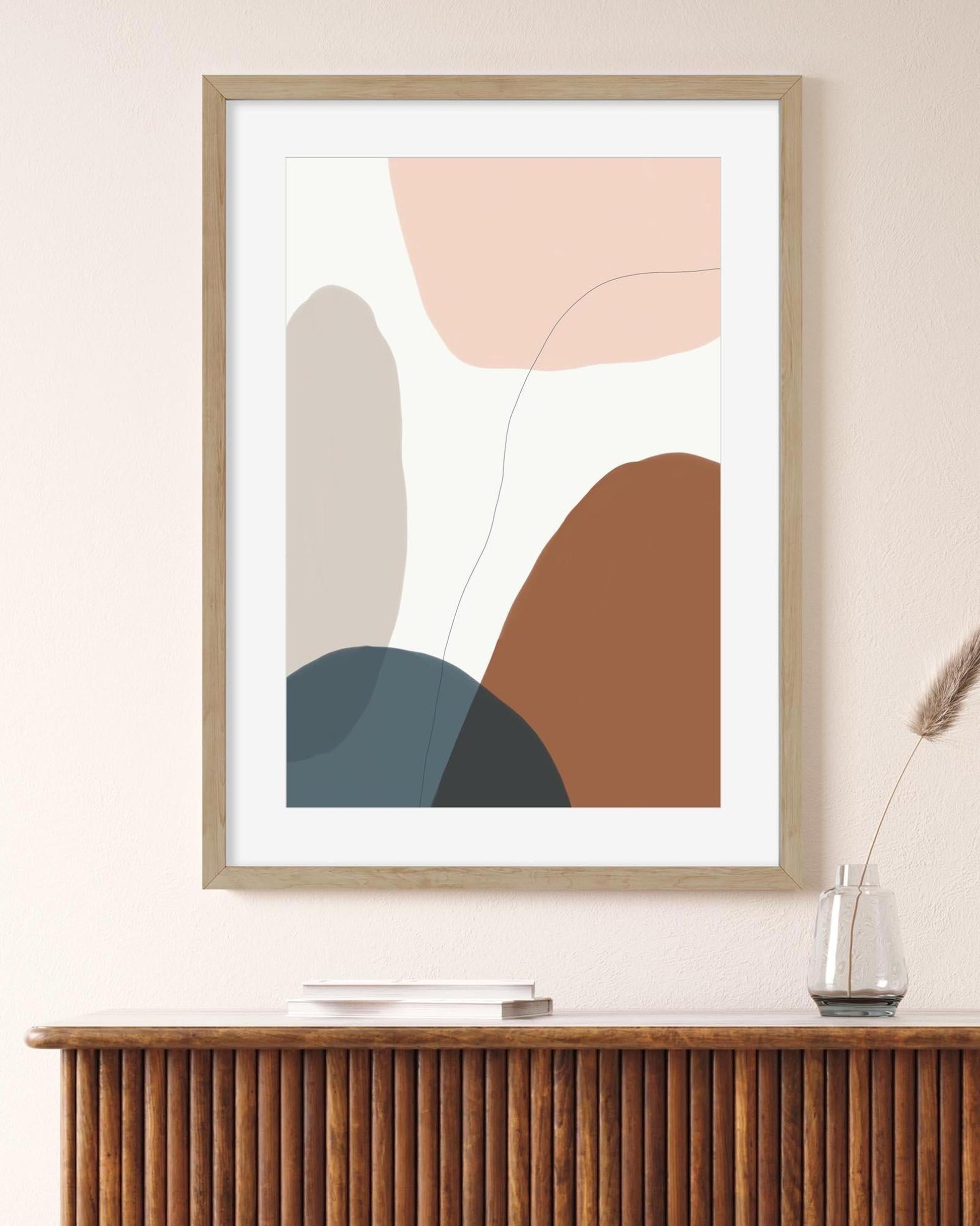 Abstract art print with geometric shapes in pastel colors on a wall above a wooden console table.