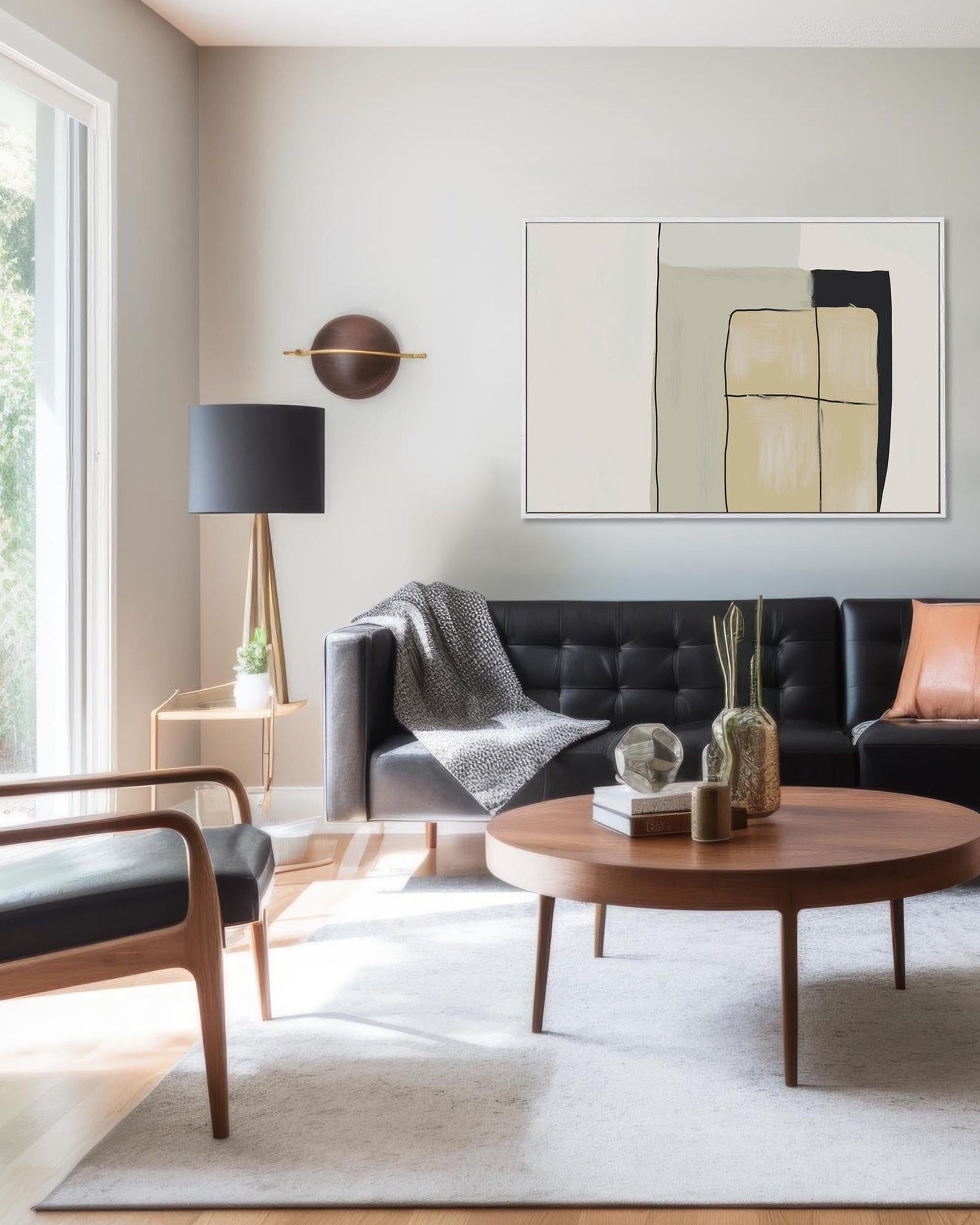 Modern living room with a black sofa, round wooden coffee table, and abstract art on the wall.