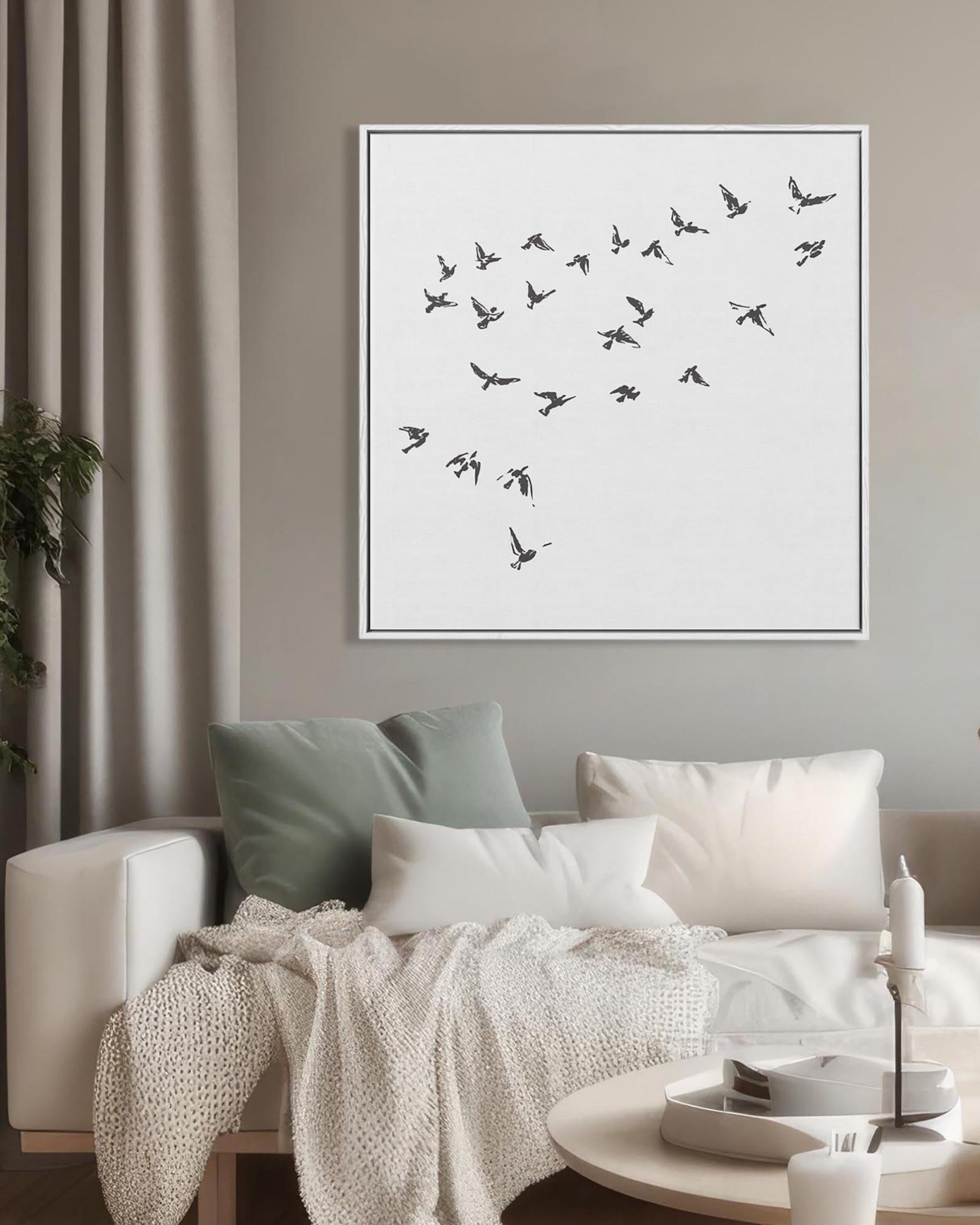 Framed artwork of birds on a wall above a sofa in a living room.