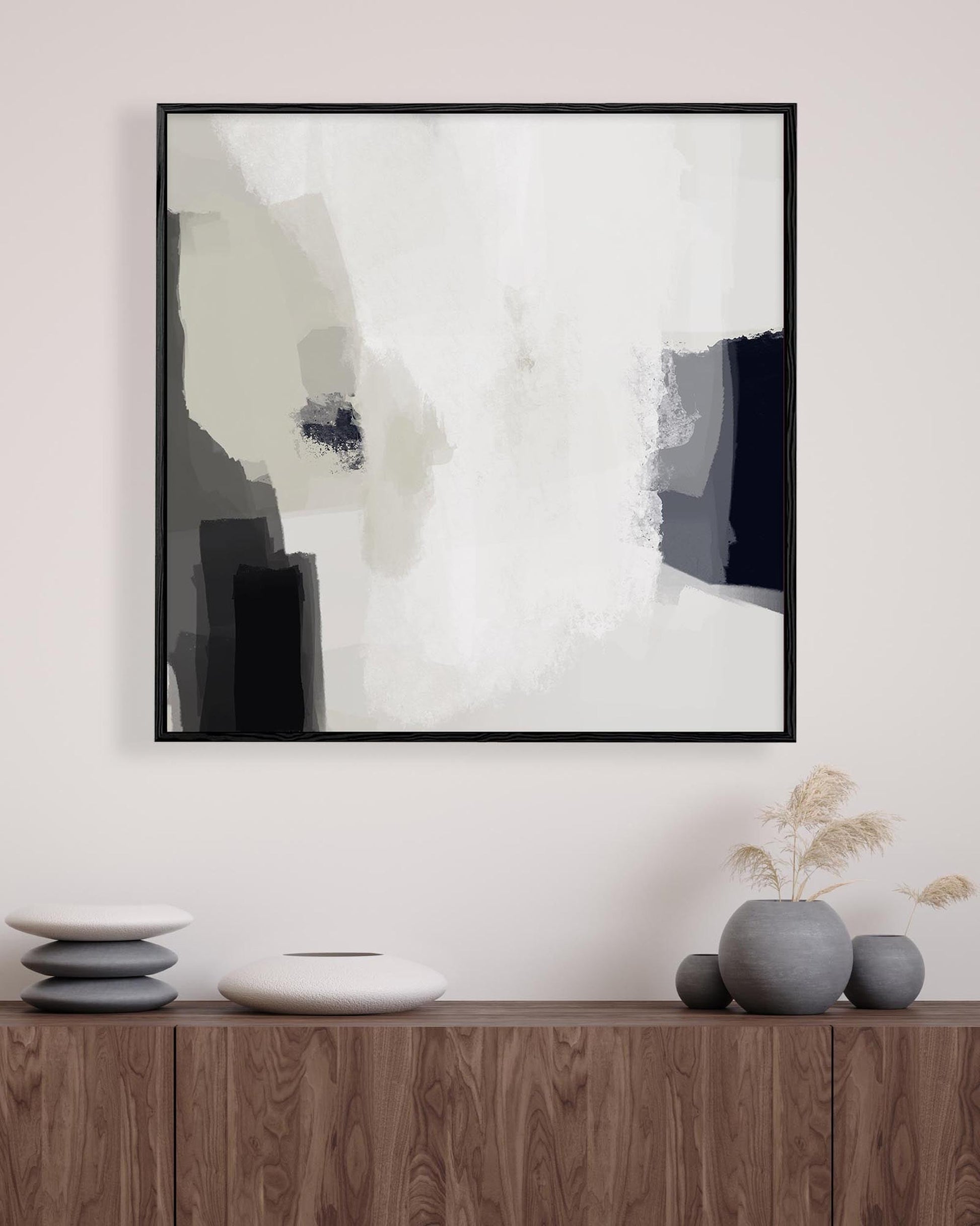 Abstract art print in a black frame on a wall above a wooden console table with decorative items.