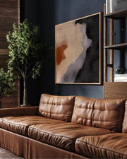 A modern abstract painting in black, grey, and terracotta tones, displayed above a brown leather sofa in a room with dark walls and a bookshelf.