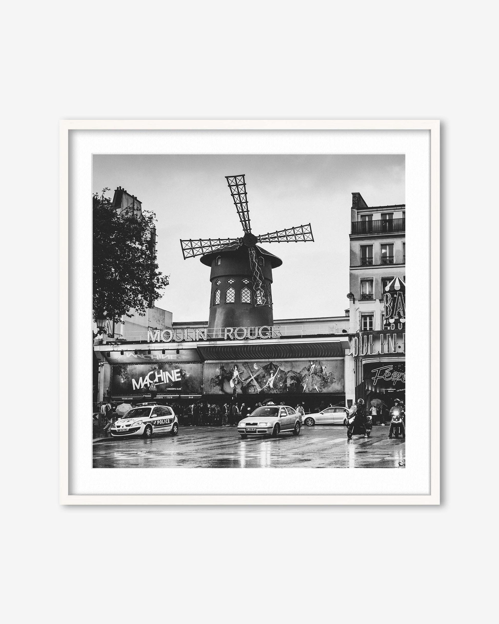 Framed black and white photo of the Moulin Rouge in Paris with cars on the street.