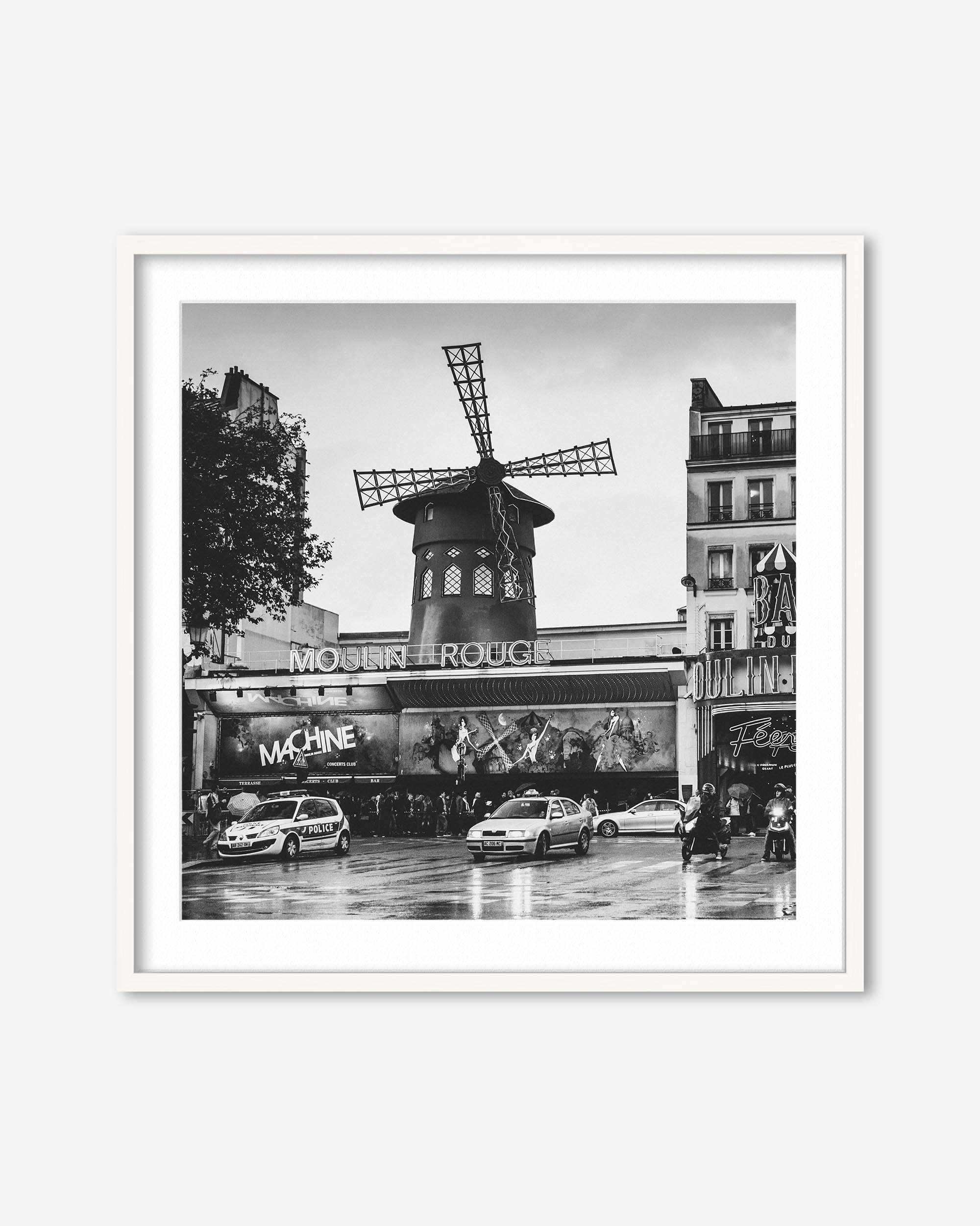 Framed black and white photo of the Moulin Rouge in Paris with cars on the street.