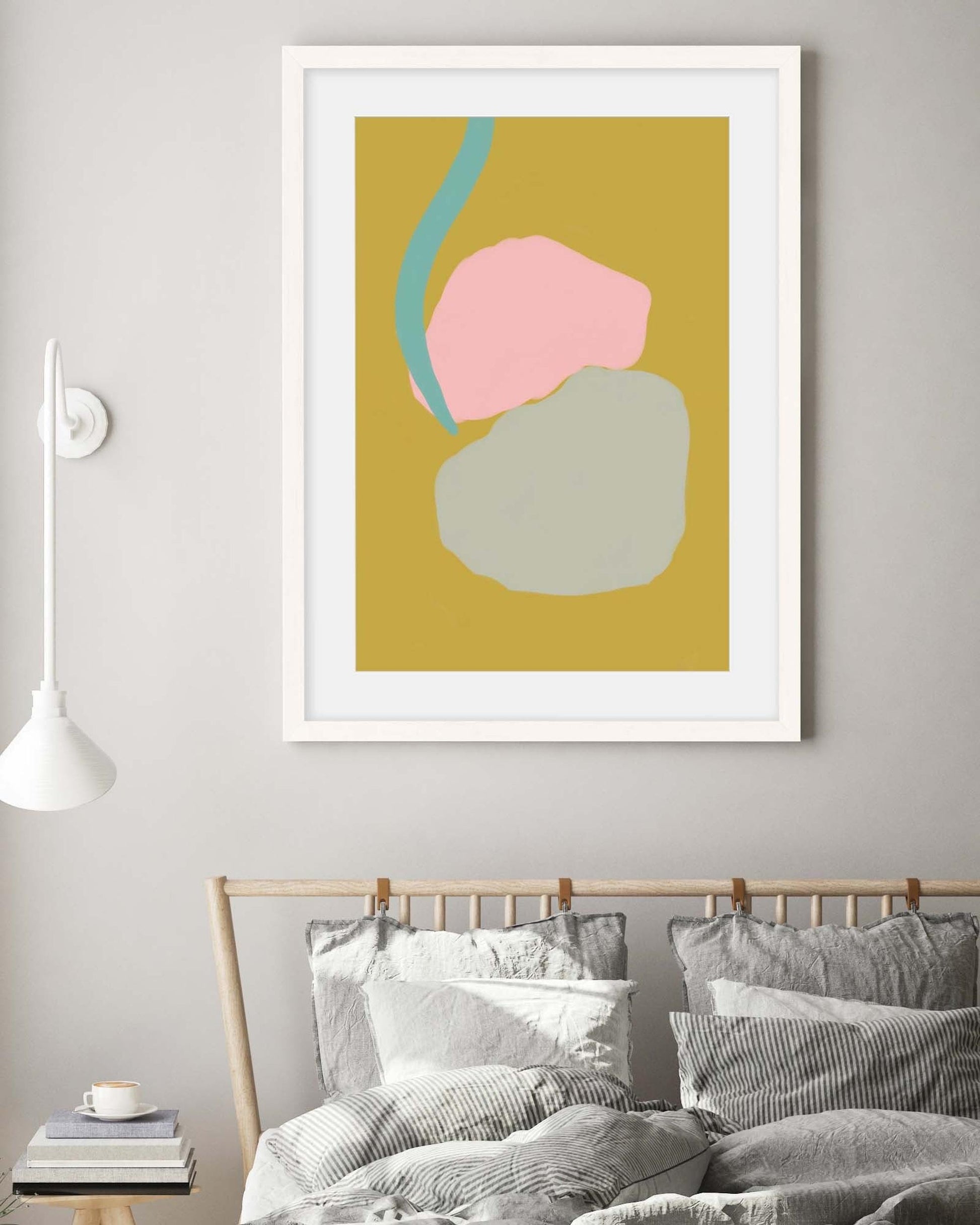 Framed abstract art print on a wall above a bed in a bedroom.