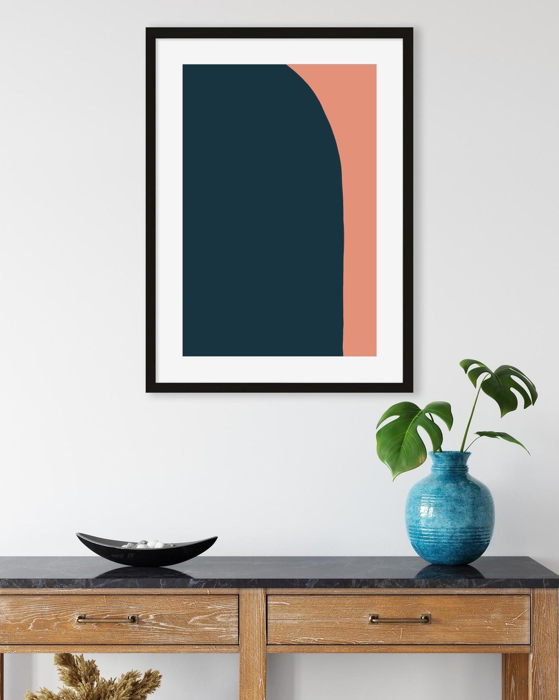 Framed abstract art piece on a wall above a wooden console table with decorative items.