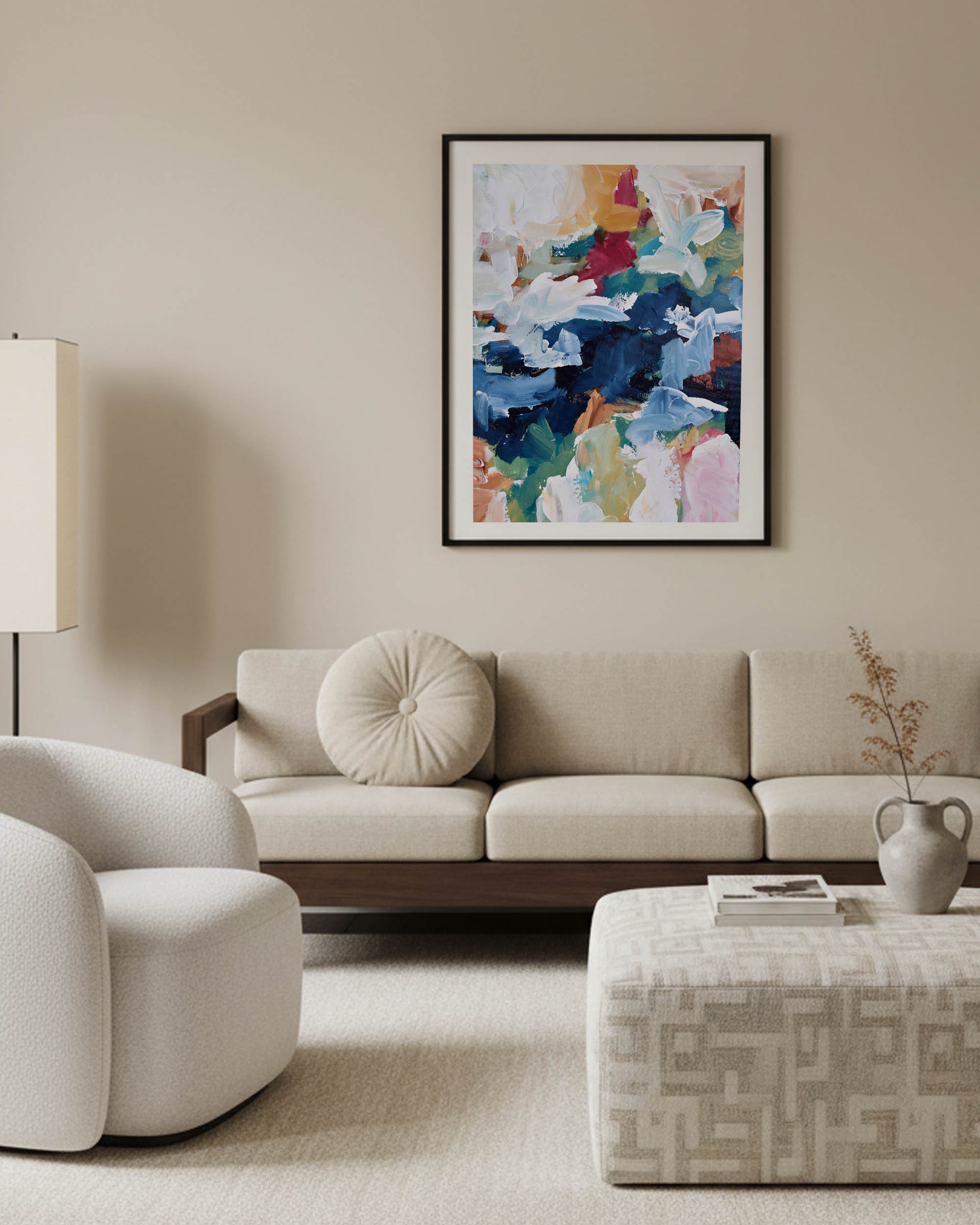 Modern living room with a beige sofa, armchair, and abstract art on the wall.