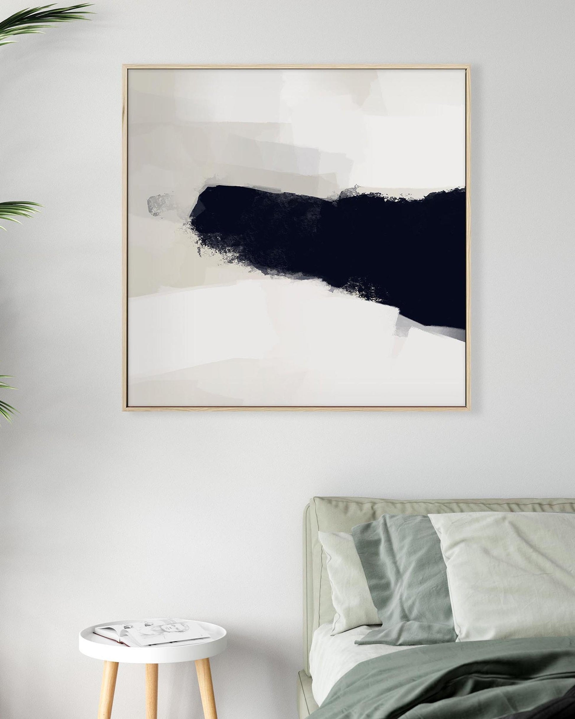 Abstract art print in a gold frame on a wall above a bed.